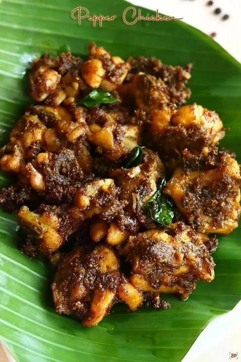 Cooked spicy pepper chicken pieces on a green banana leaf.