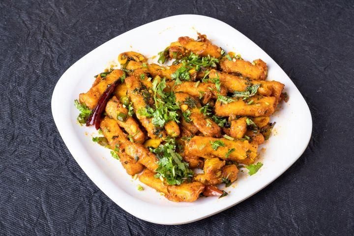 Fried strips of vegetables, garnished with fresh cilantro, served on a white plate.