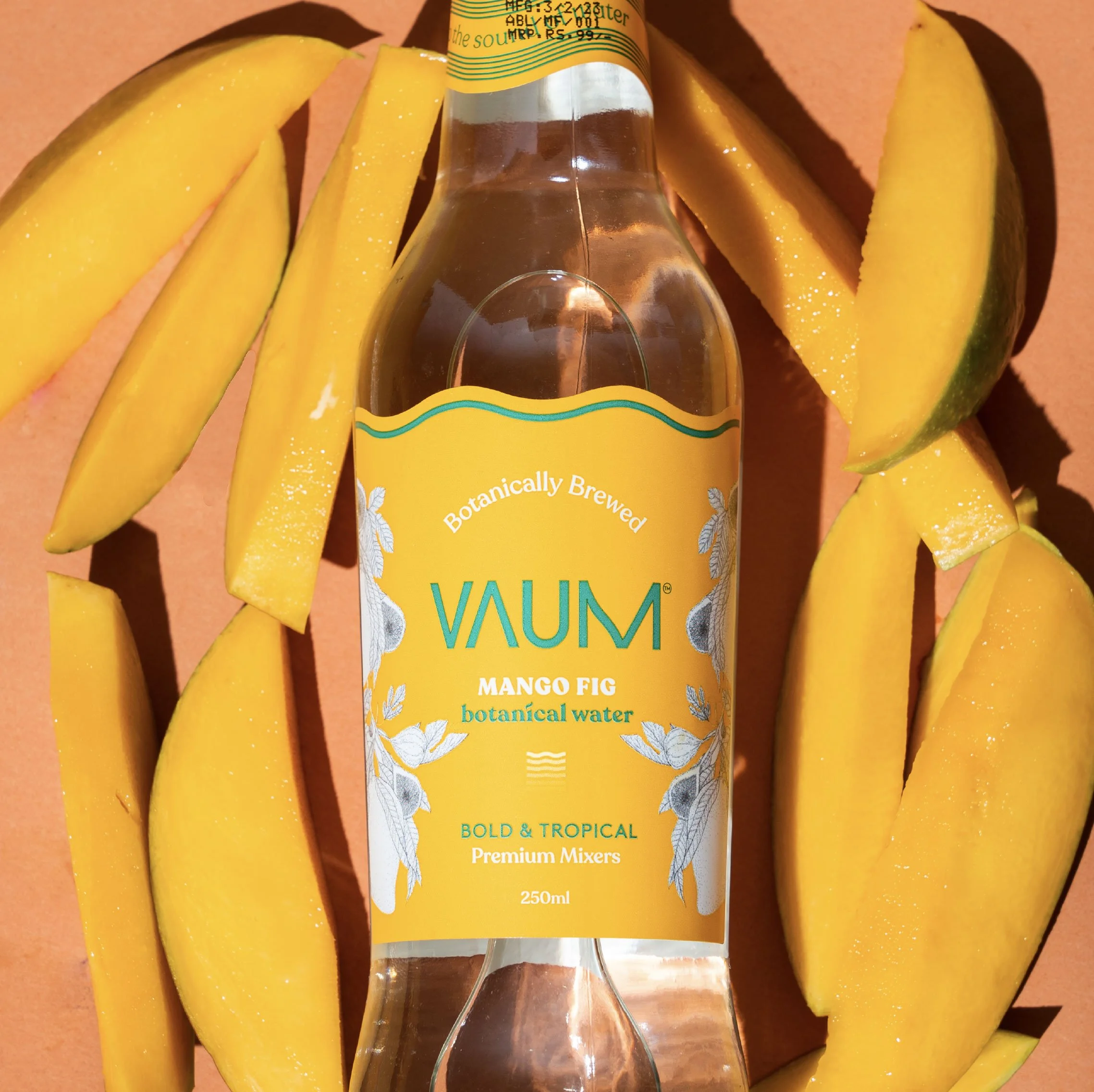 A bottle of ValuM mango flavor botanical water surrounded by sliced mango pieces on a peach-colored background.
