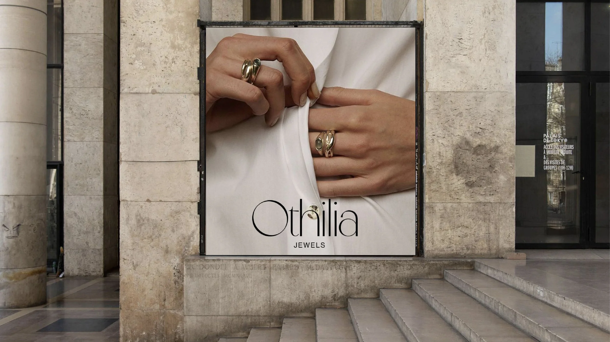 Poster for Othilia Jewels showing two hands with rings adjusting a white fabric. The building has stone walls and steps, with glass doors on the right side.
