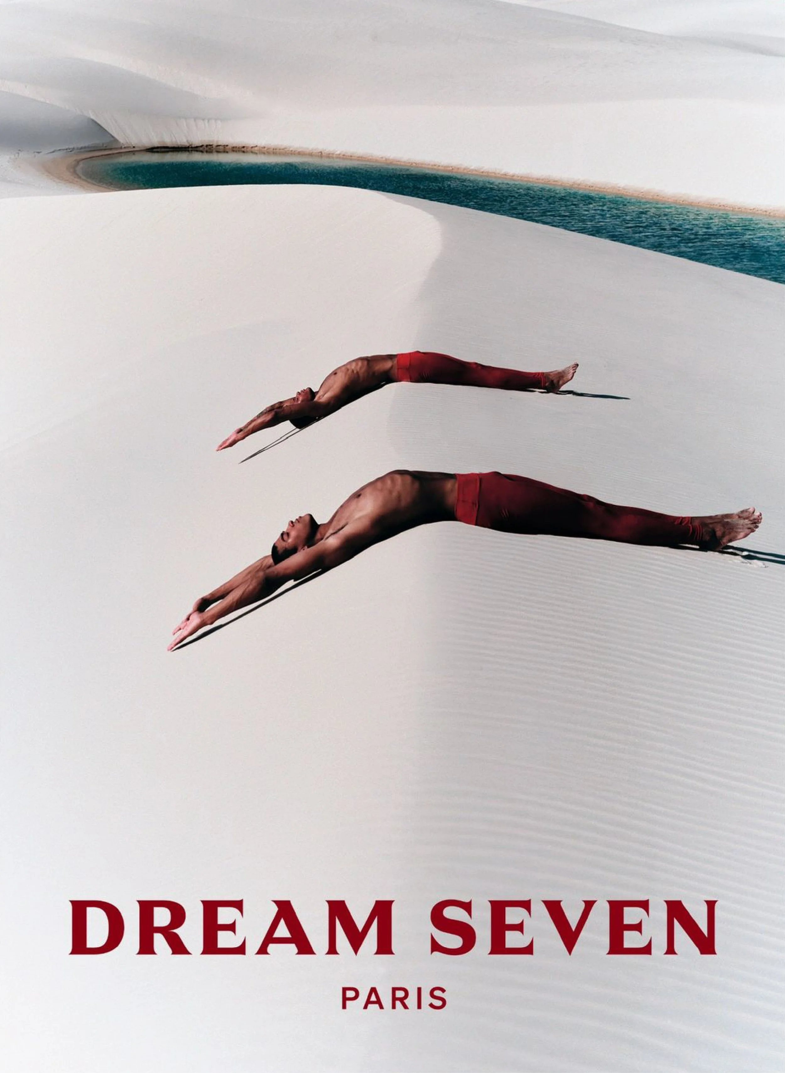 A minimalist advertisement poster featuring two dancers in red pants, extending their bodies horizontally on a white background with subtle curved patterns, and the words 'DREAM SEVEN PARIS' in bold red text at the bottom.