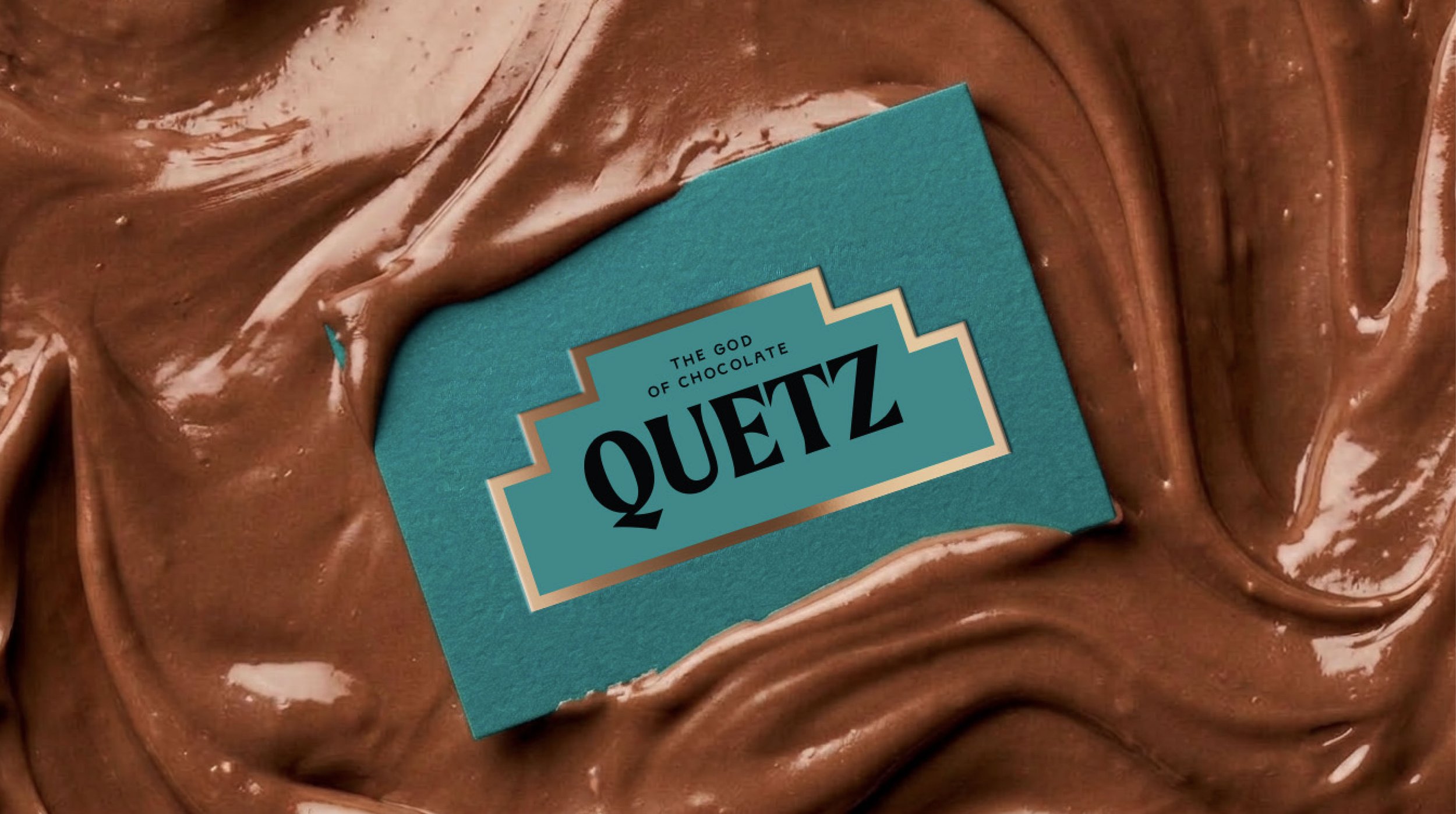 Close-up of a chocolate spread with a label that reads "Quez, The God of Chocolate," on a textured brown surface.