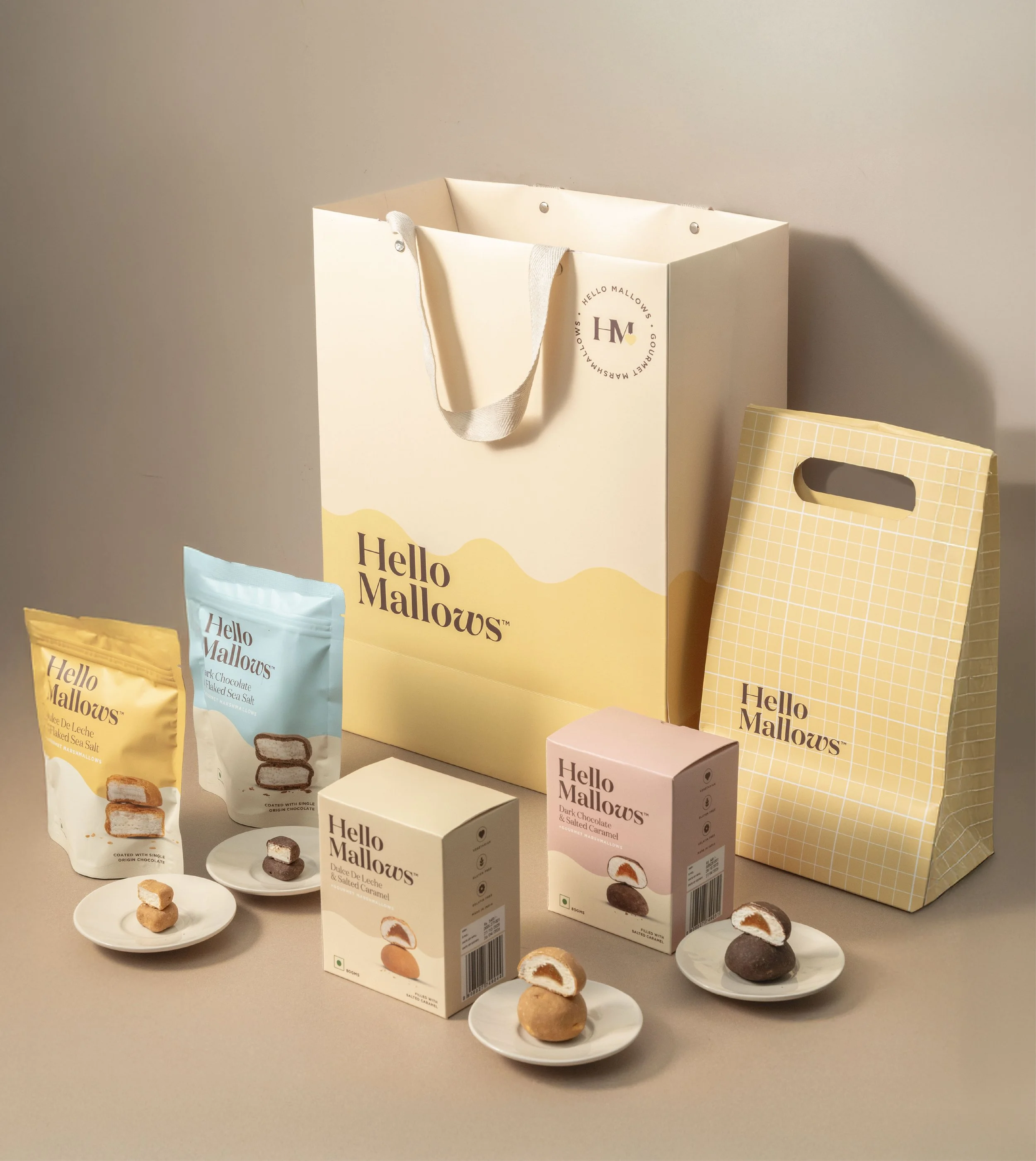 Assorted Hello Malloews snack packages and small plates with different kinds of filled chocolates on a table.