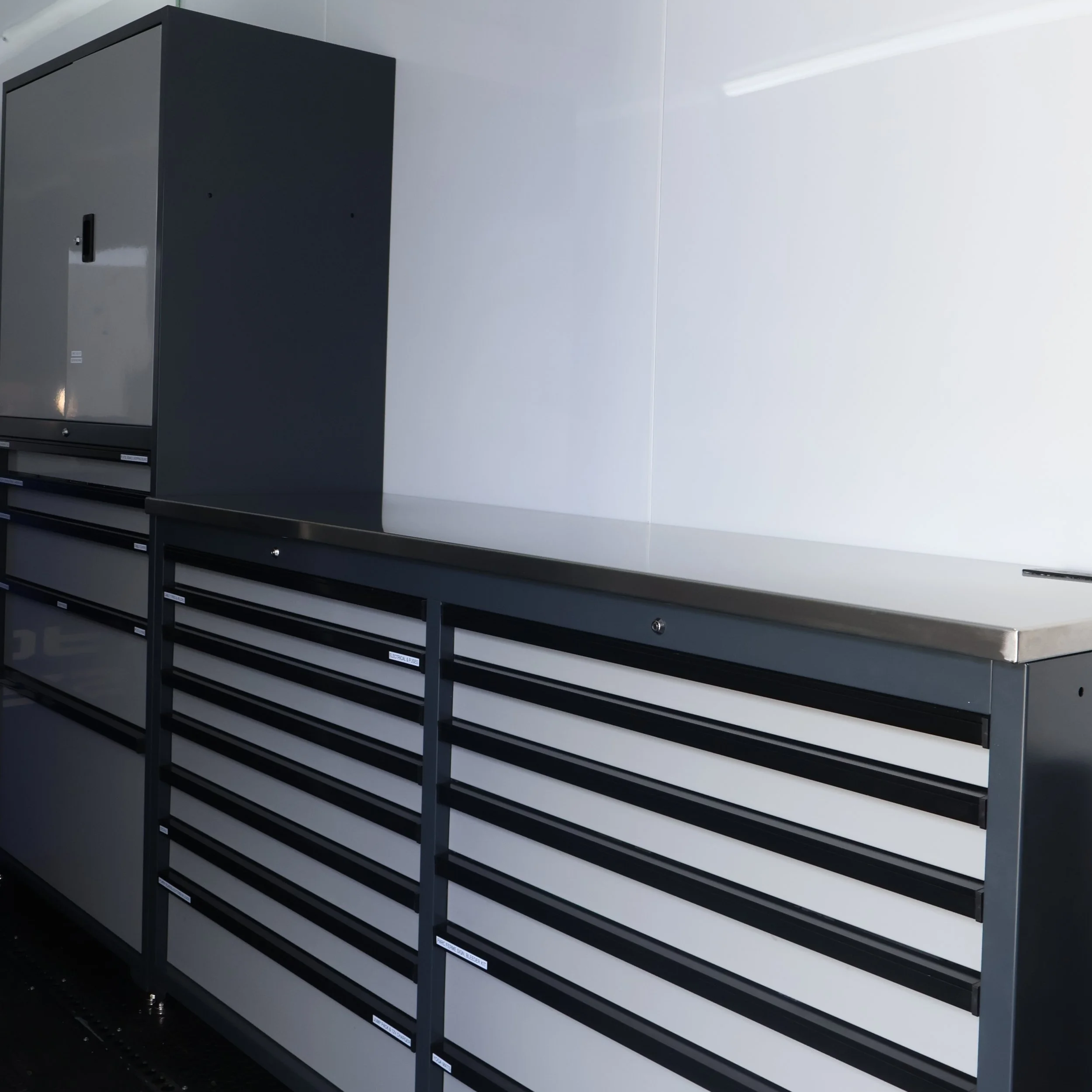 Empty black and white storage cabinets with small labels in a modern office or workshop setting.
