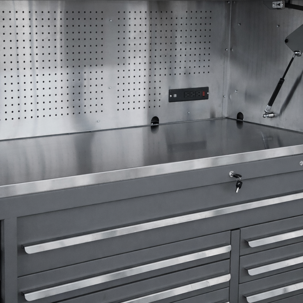 A stainless steel workbench with drawers, electrical outlets, and a pegboard wall, used in a workshop or industrial setting.