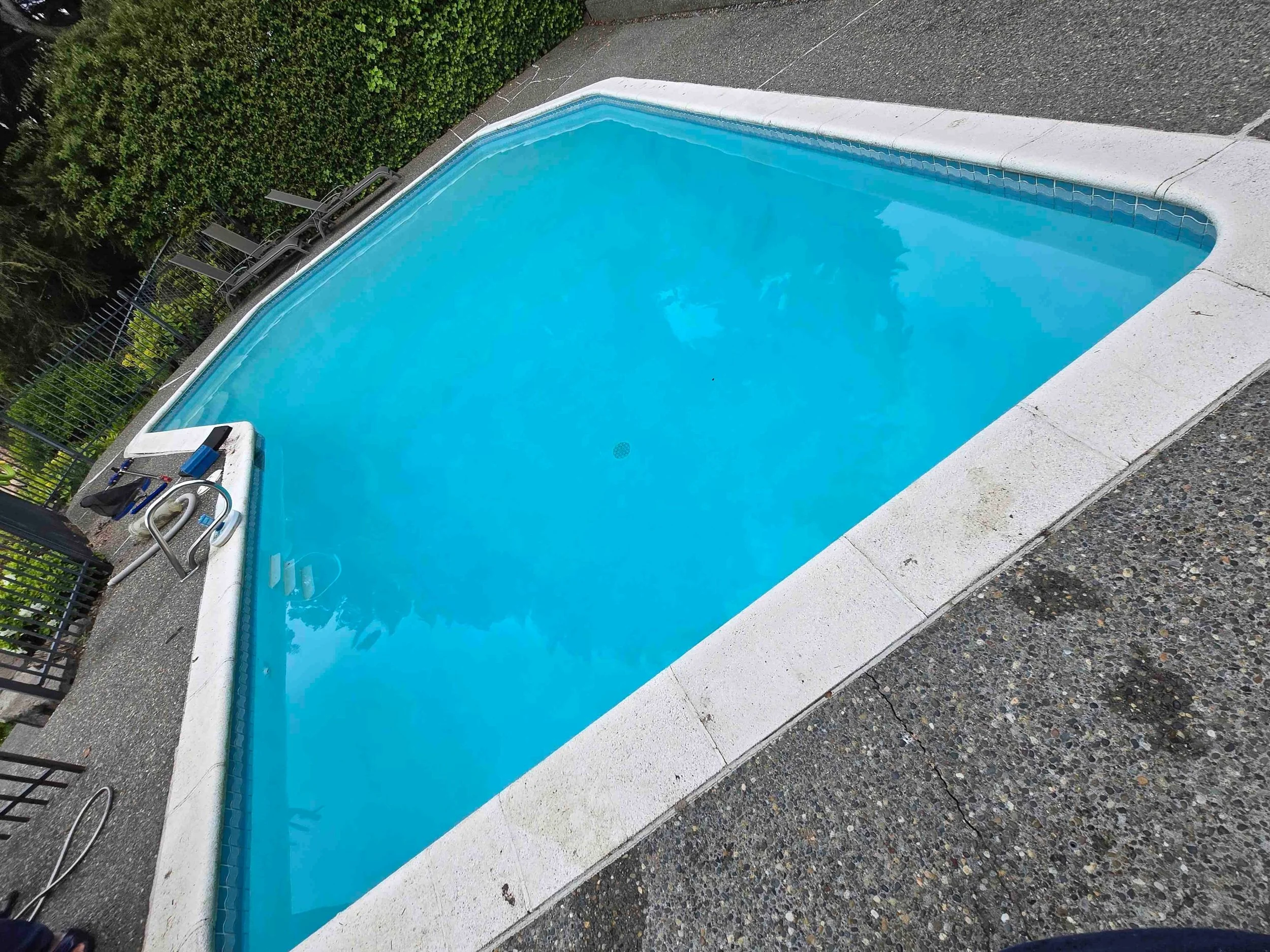 A clear blue backyard swimming pool with light blue water.