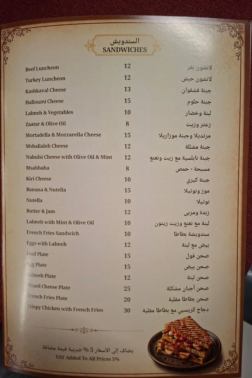 Menu of sandwiches with Arabic descriptions and prices in USD, includes options like beef luncheon, turkey luncheon, various cheese sandwiches, and fried chicken with French fries, with a small picture of a sandwich at the bottom right.