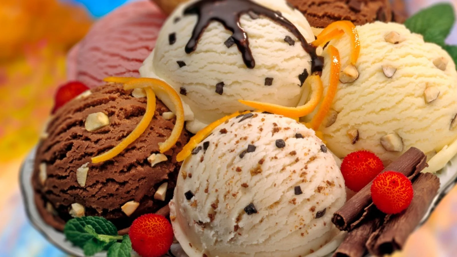 Assorted scoops of ice cream with chocolate, vanilla, and strawberry flavors topped with chocolate sauce, orange peel, nuts, and garnished with strawberries, chocolate sticks, and mint leaves.