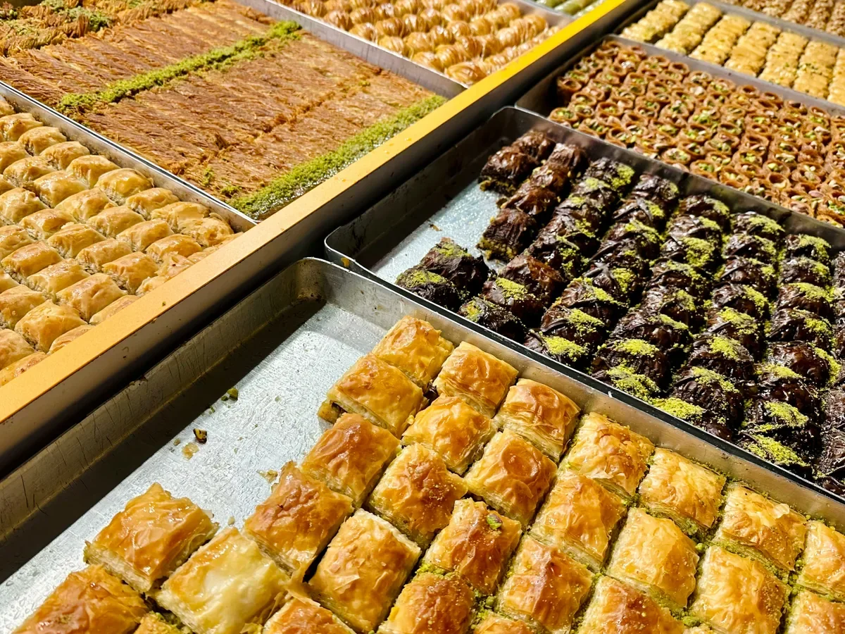 Assorted Middle Eastern desserts displayed in trays, including baklava and other sweets.