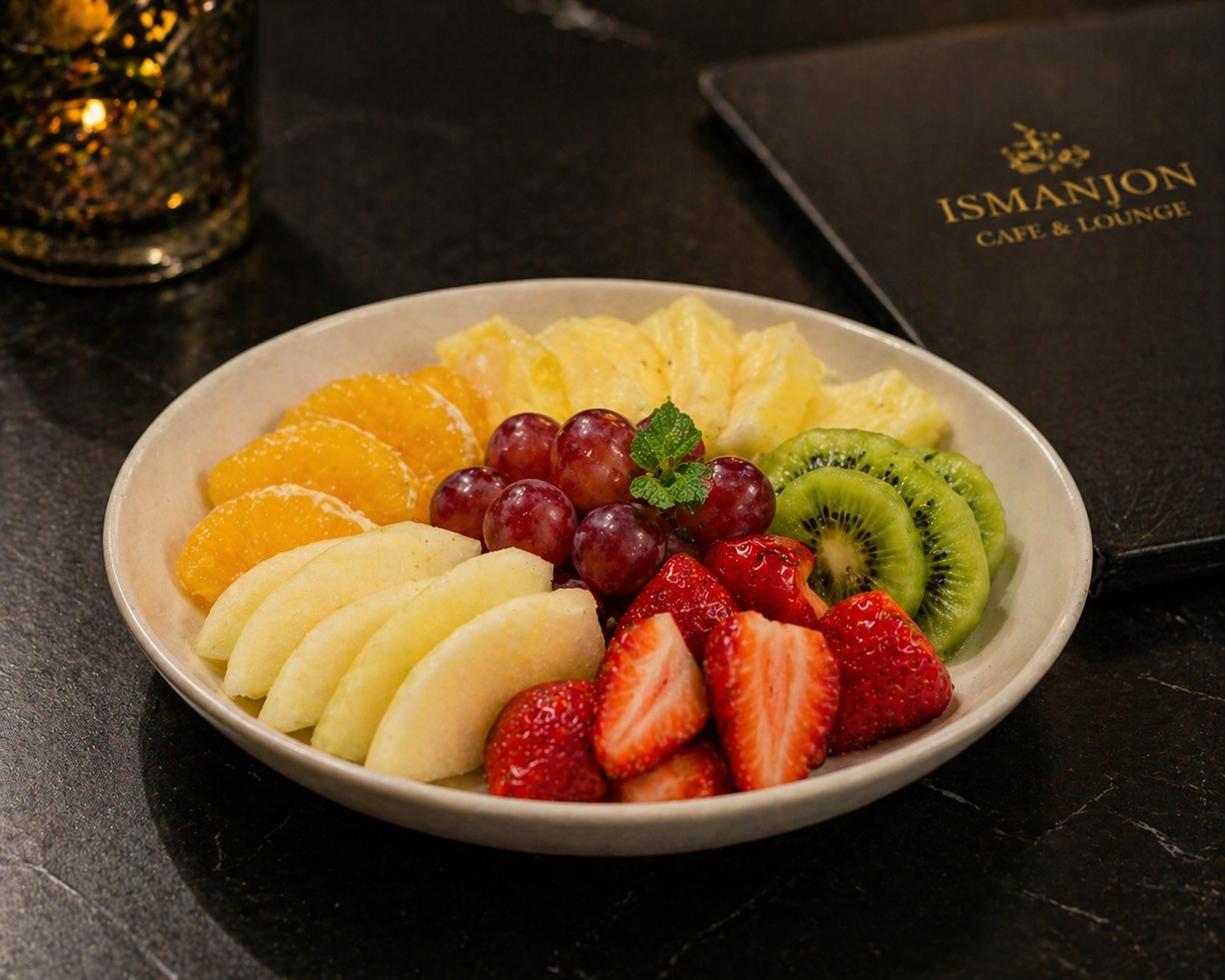 A white bowl filled with assorted sliced fresh fruits including strawberries, kiwi, grapes, peaches, apples, and oranges on a dark surface.