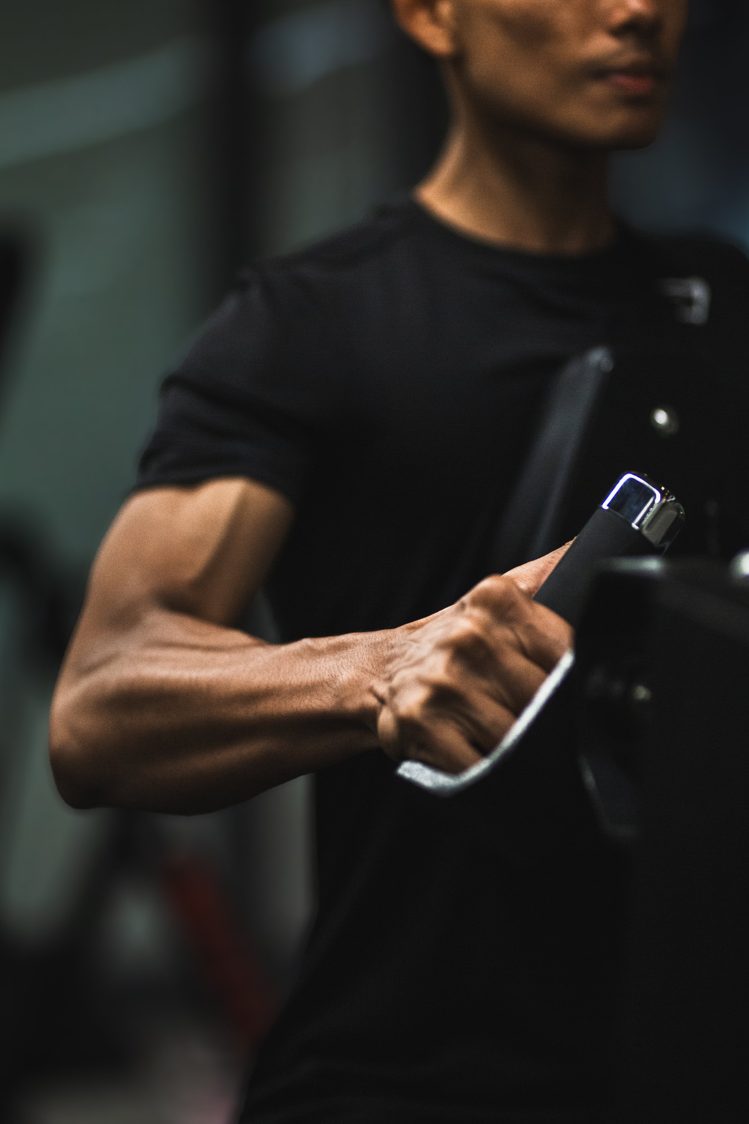 Close-up of a person wearing a black shirt, holding a smartphone, with focus on their arm and hand.