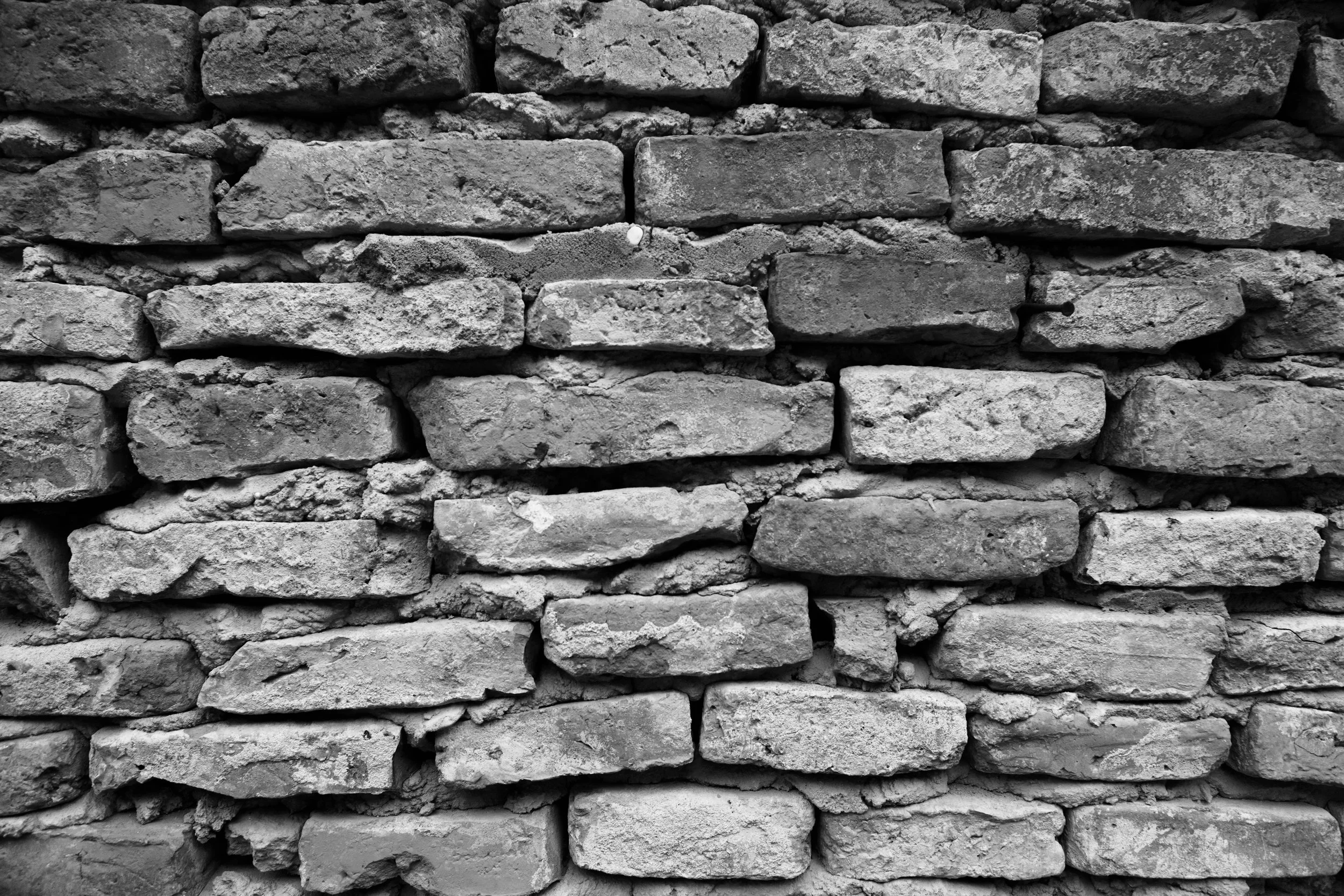 Schwarz-weiß-Bild einer alten, unregelmäßigen Backsteinmauer.