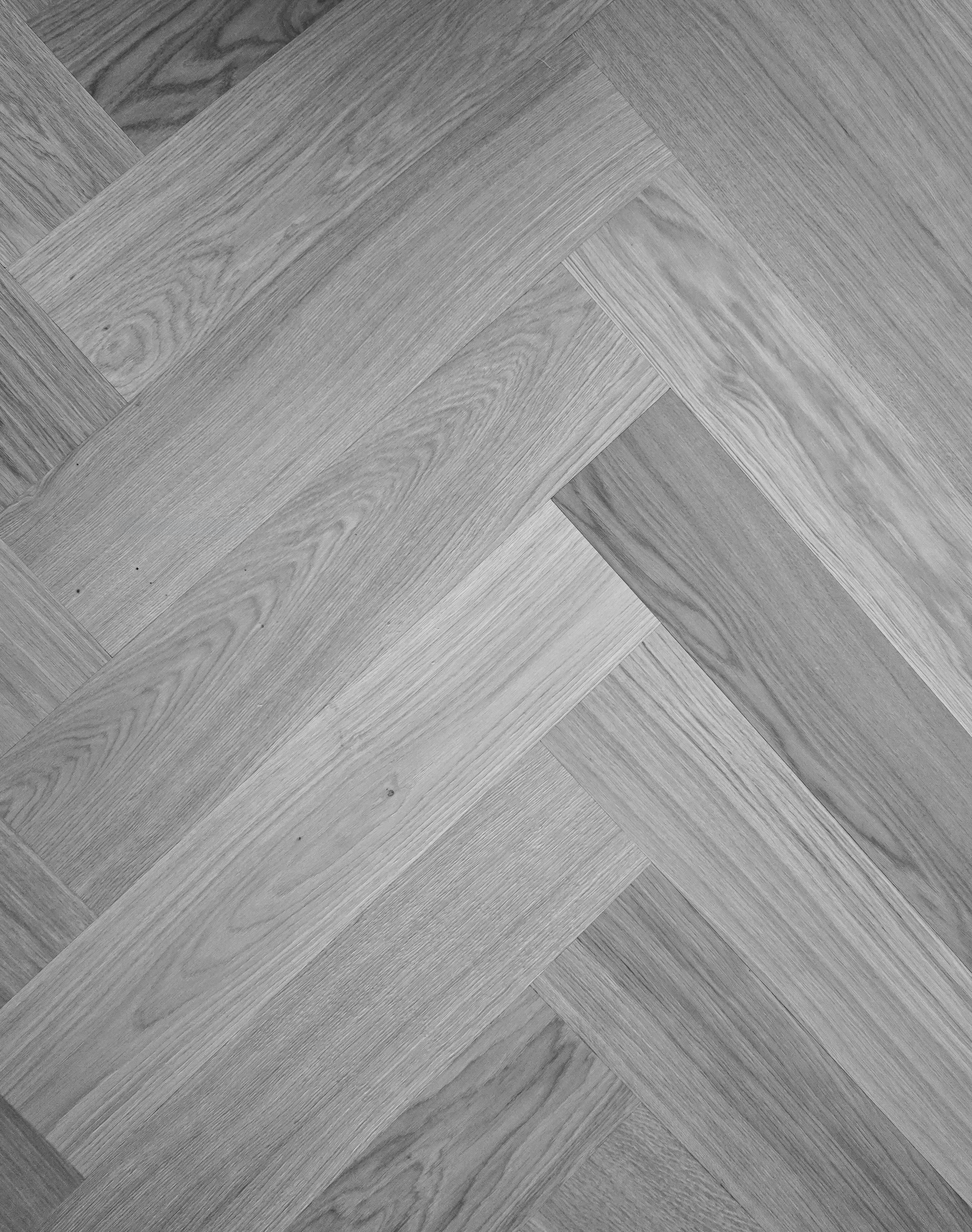 Schwarz-weiß-Bild eines Holzbodenmusters mit geometrischem Design aus verschiedenen Holzarten und Holzmaserungen.