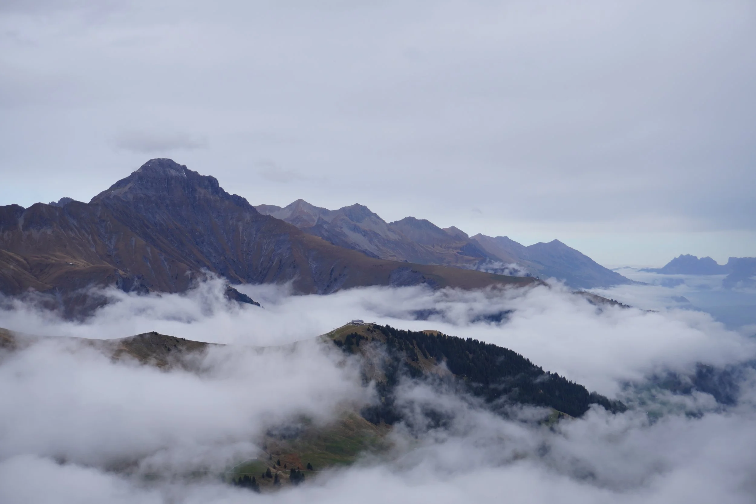 Berglandschaft mit hohen, felsigen Gipfeln, umgeben von Wolken und Nebel