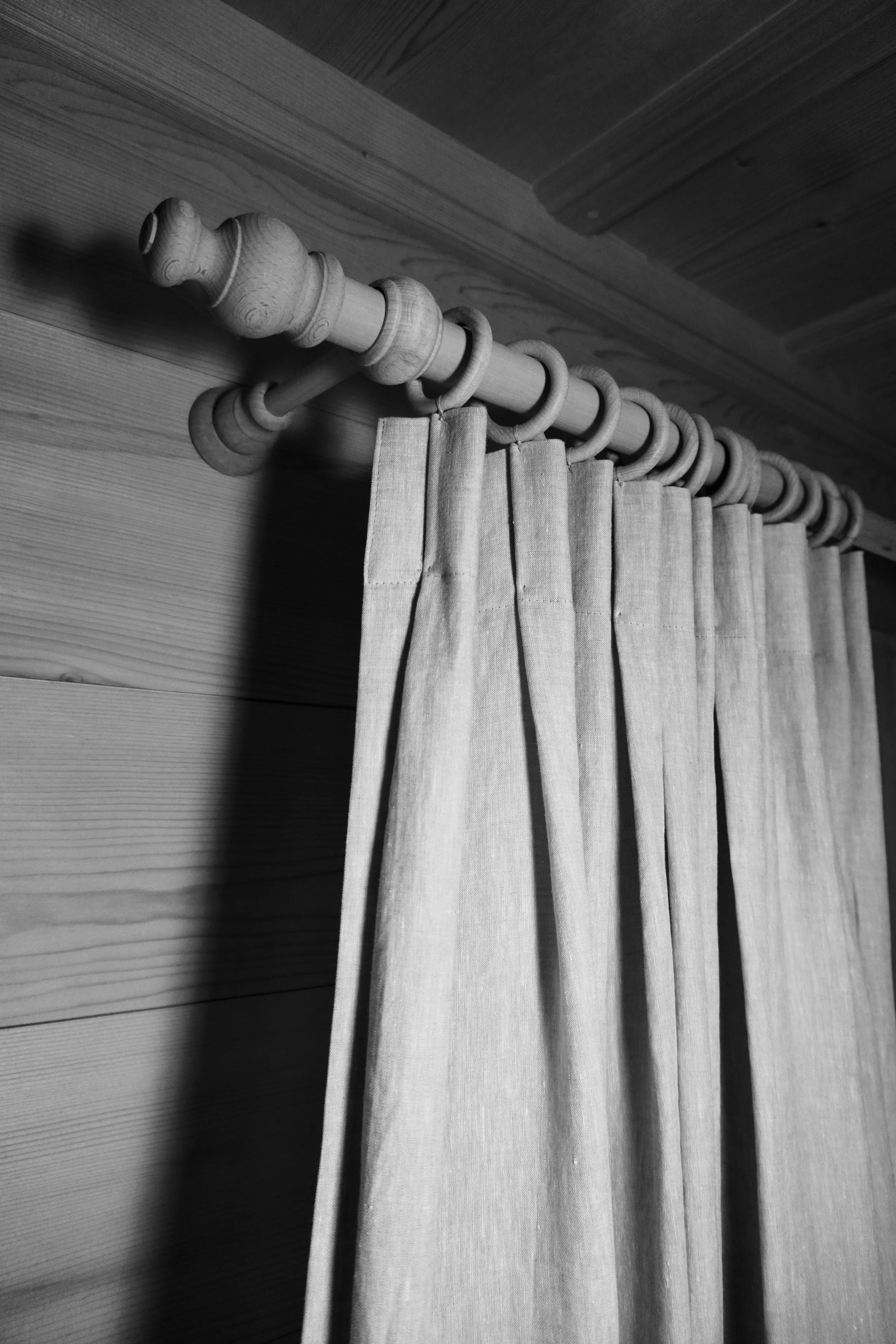 Schwarzer und weißer Stoffvorhang an einem Holzvorhangstang an einer Wand.