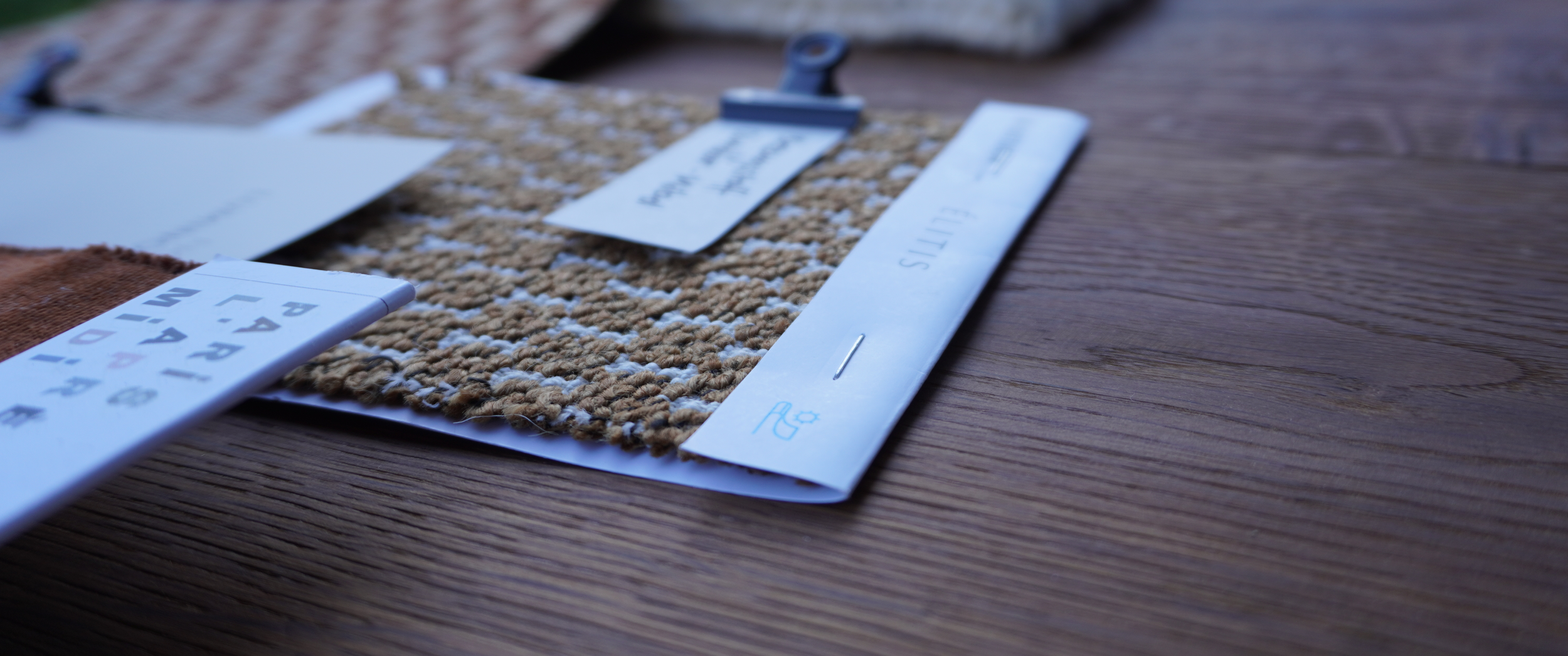 Etiketten und Muster auf einem Teppichmuster liegen auf einem Holztisch.
