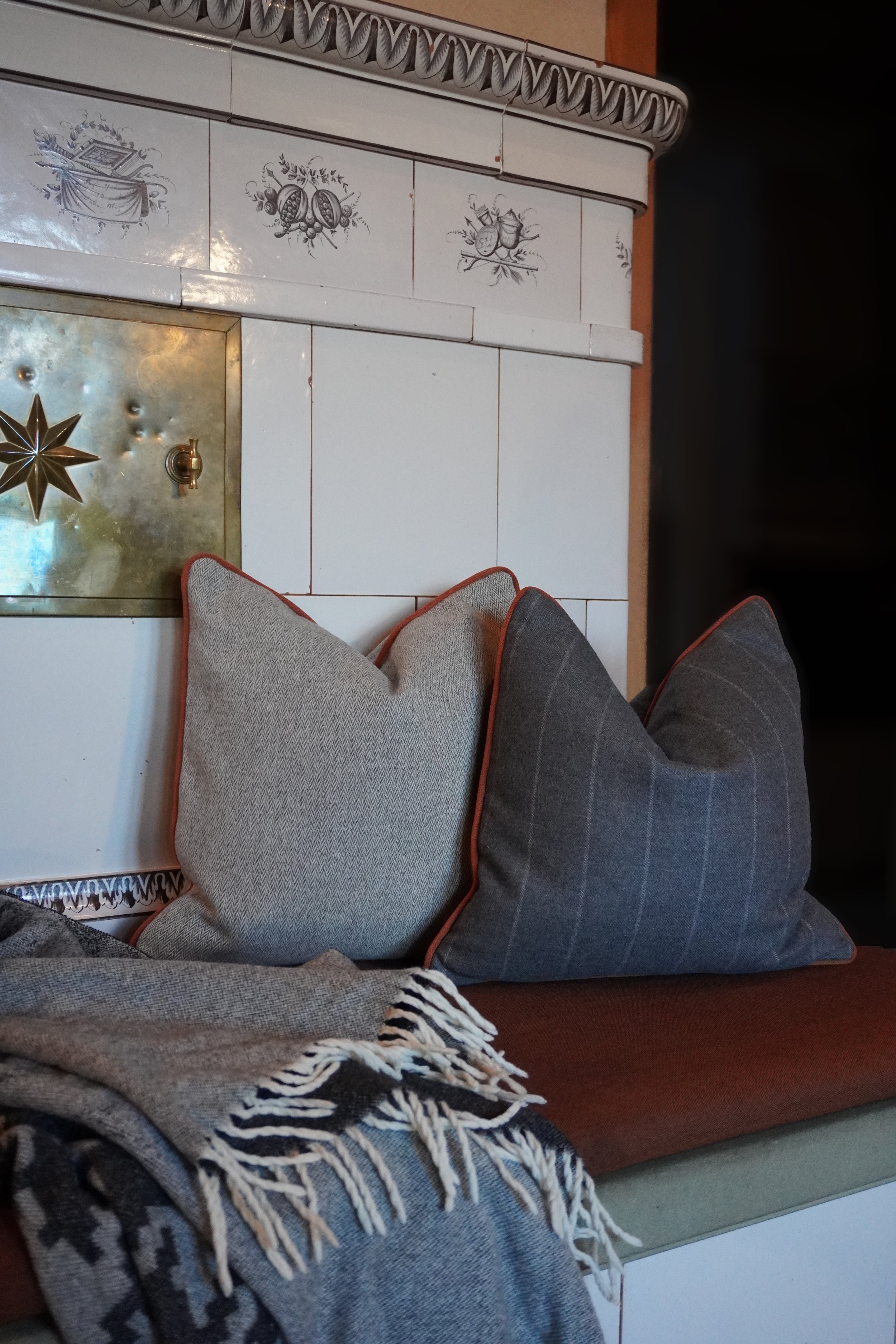 Blick auf die Füße einer Person, die auf einem Sofa sitzt, mit einem grauen und weißen gestrickten Decke in einer Wohnung.