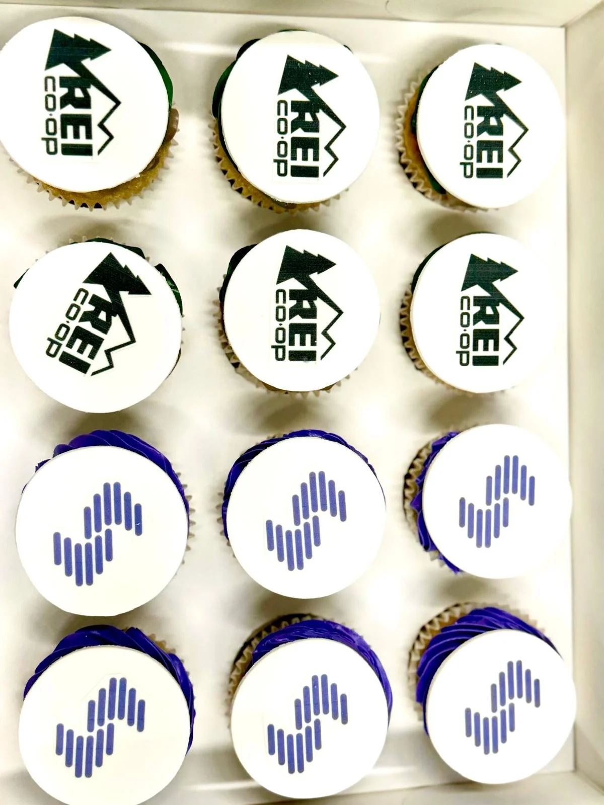 A box of cupcakes with top decoration featuring the logos of KAEQ and Audacy.