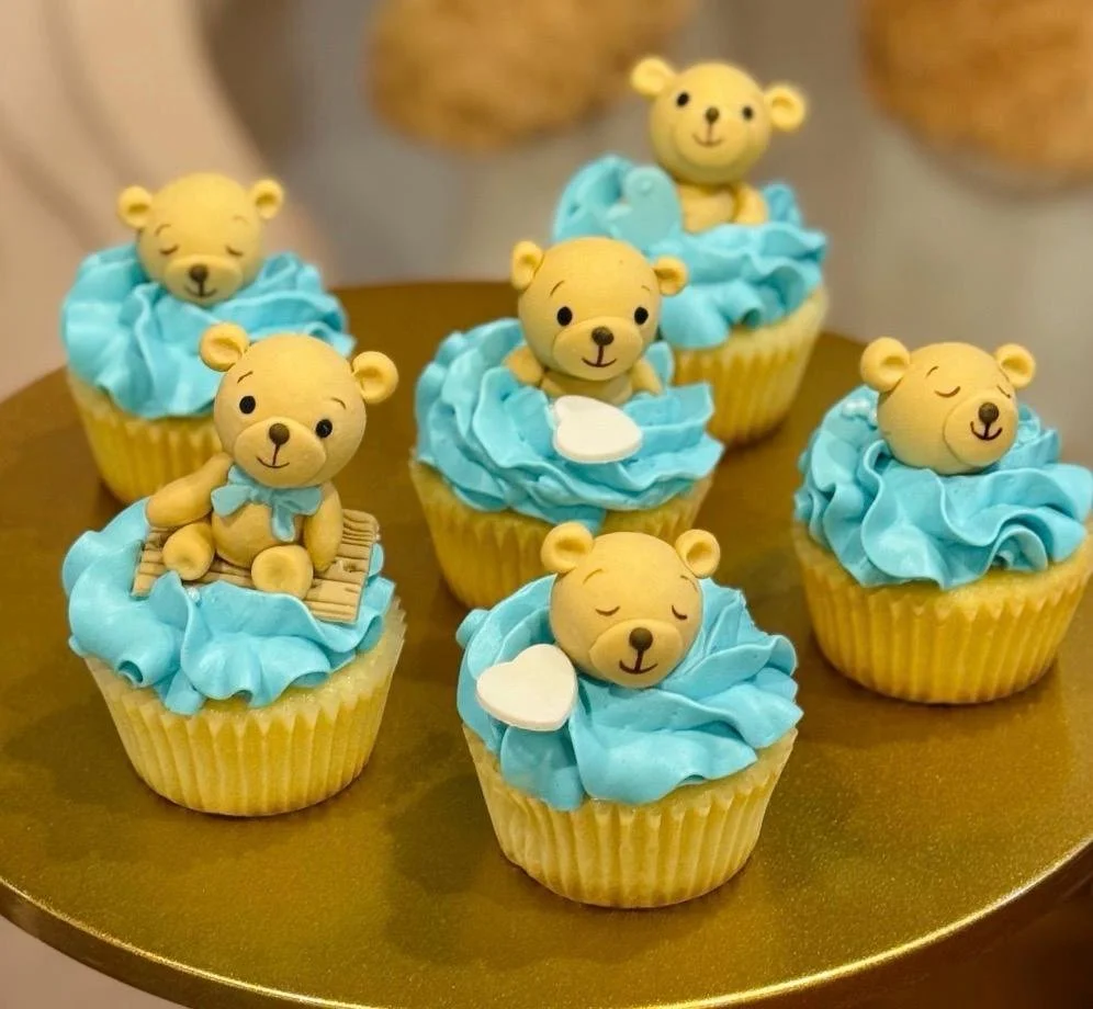 Cupcakes decorated with teddy bear toppers and blue frosting.
