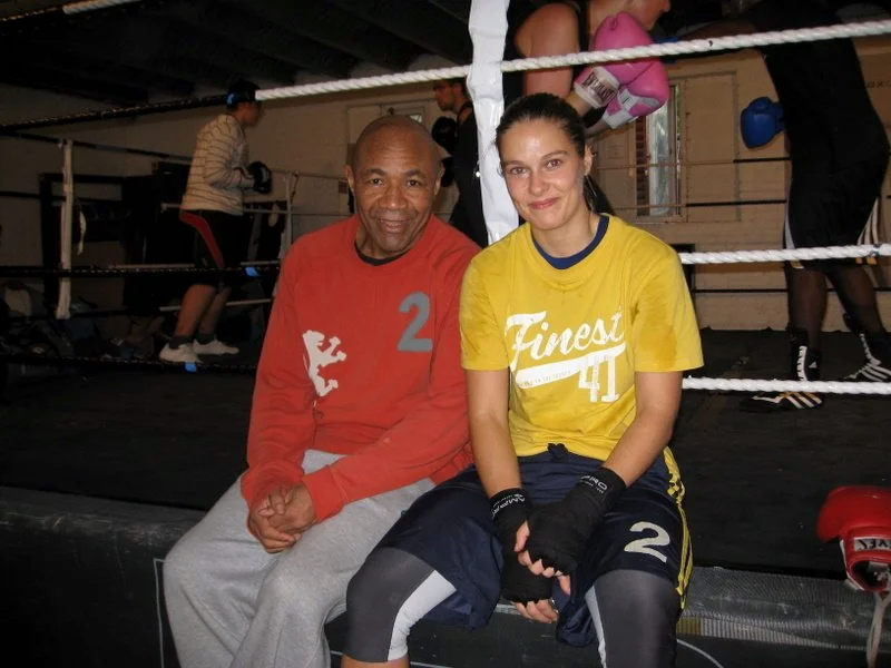 Elizabeth Banks in her early days as a boxer, sitting on the edge of the ring next to her mentor in a busy boxing gym. The moment that sparked her lifelong mission to understand movement and healing.