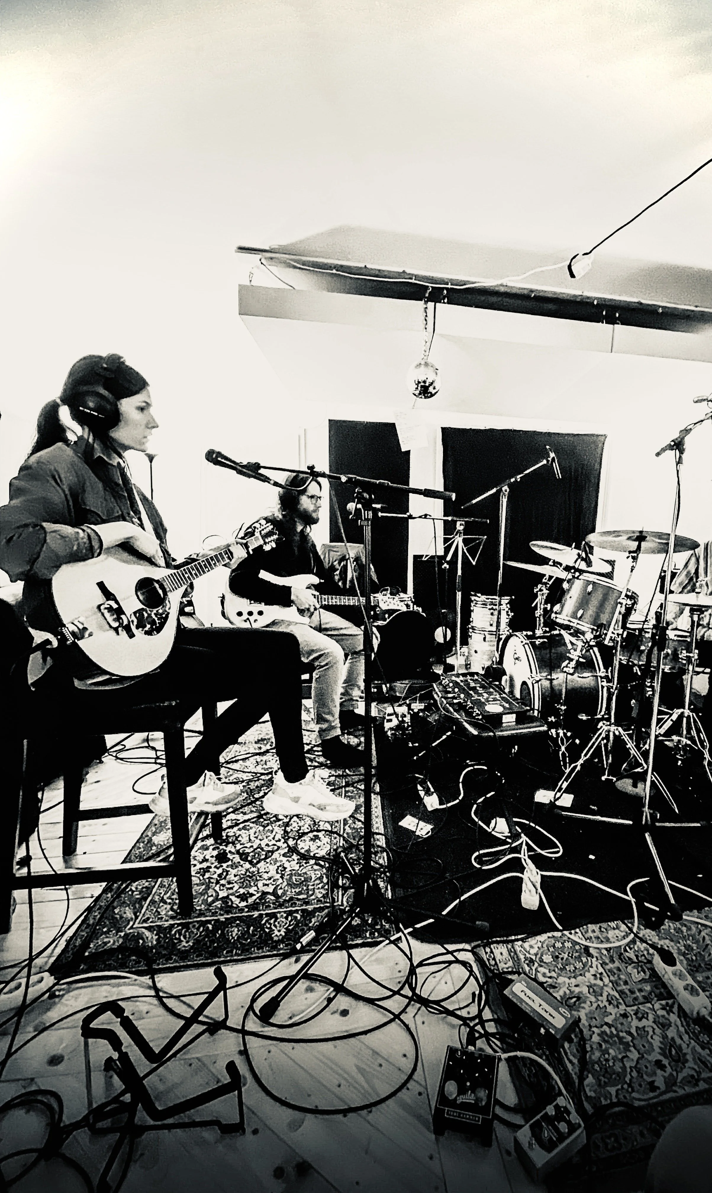 Zwei Musiker in einem Tonstudio. Einer spielt Gitarre, die andere Irish Bouzouki. Viele Kabel und Tonaufnahmetechnik im Raum.