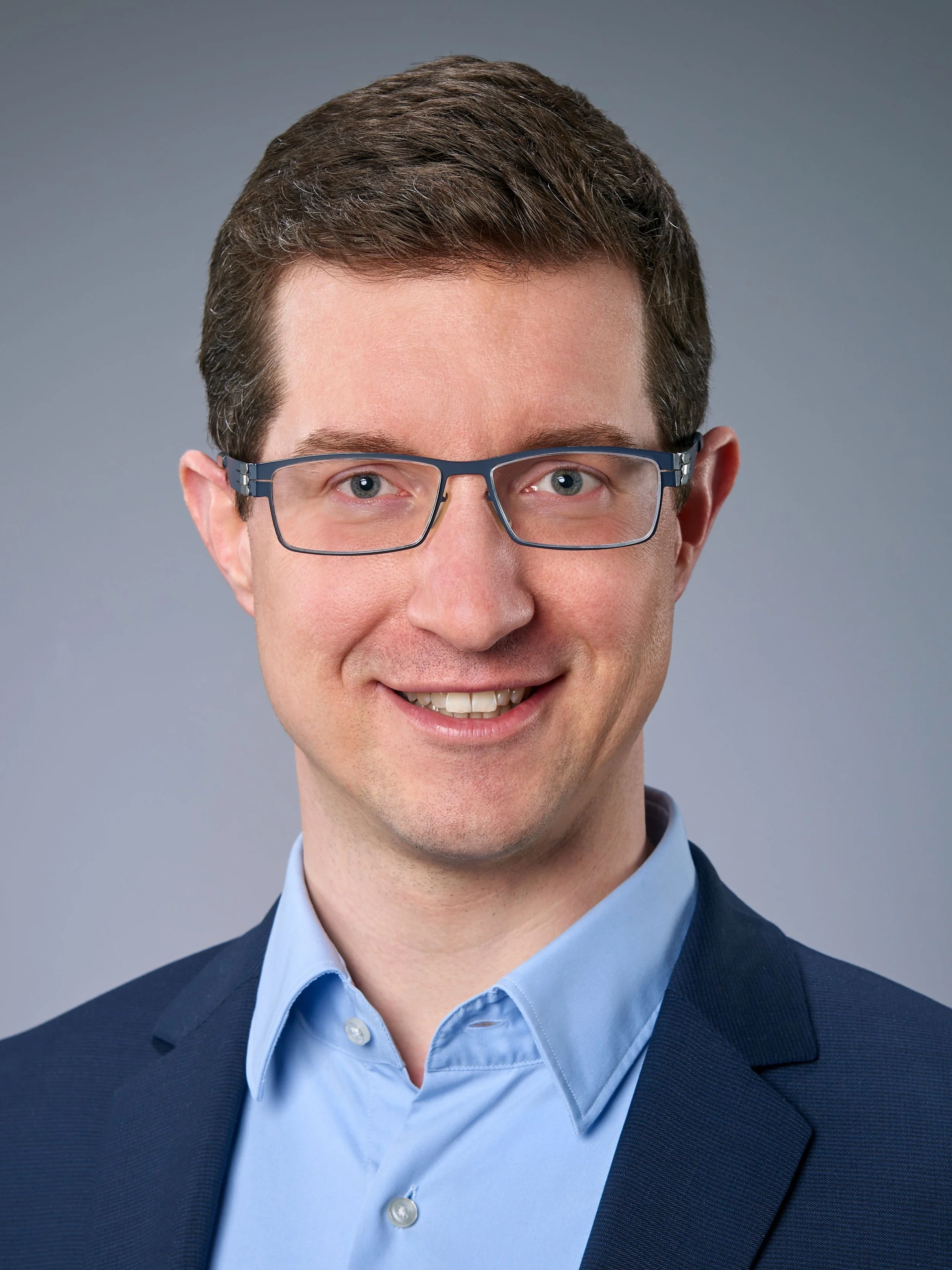 Felix Knittel, Coach für Führungskräfte, im blauen Anzug mit hellblauem Hemd vor grauem Hintergrund