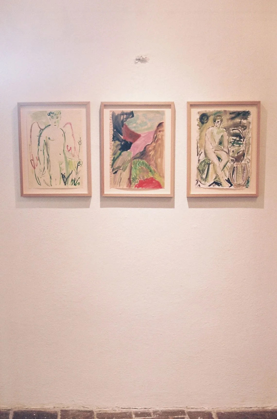 Three framed abstract paintings hung on a white wall in an art gallery.