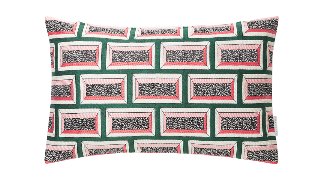 Patterned pillow with geometric shapes and leopard print accents in pink, green, white, black, and gray.