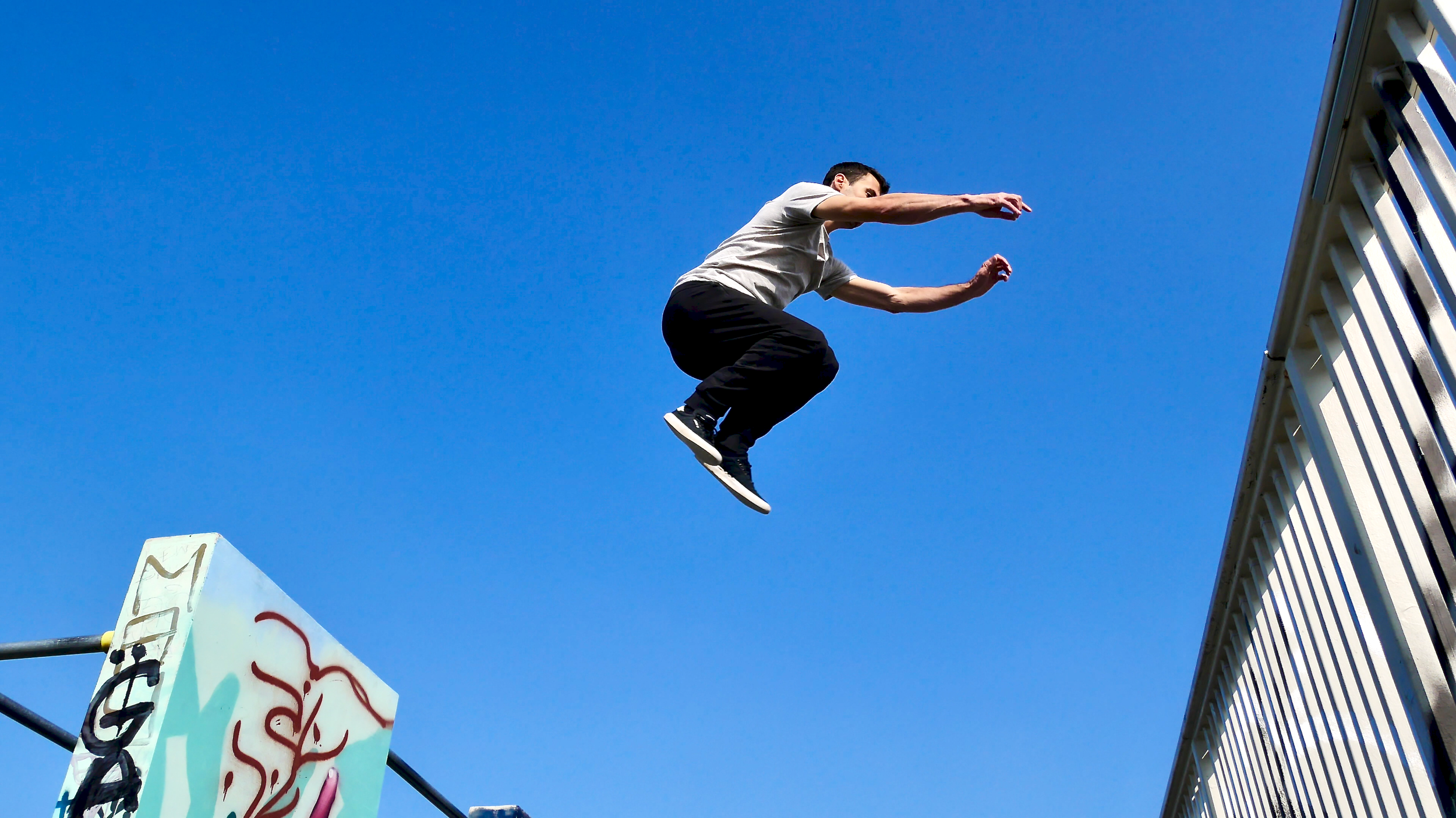 Un homme faisant du parkour, saut de précision entre un mur et une barrière
