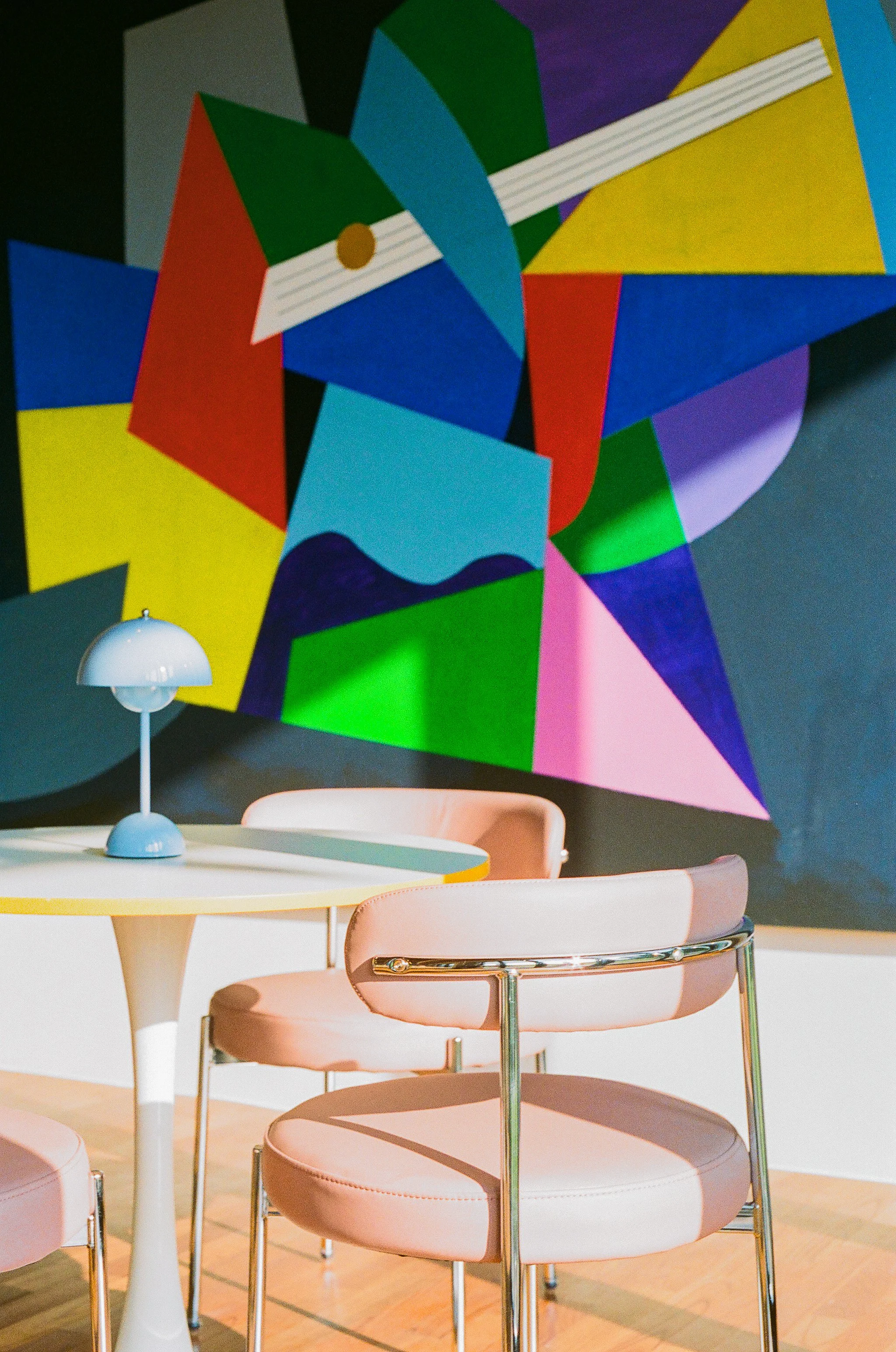 Interior of museum venue exhibiting Burnsoo Song works — colourful geometric mural with pastel seating area