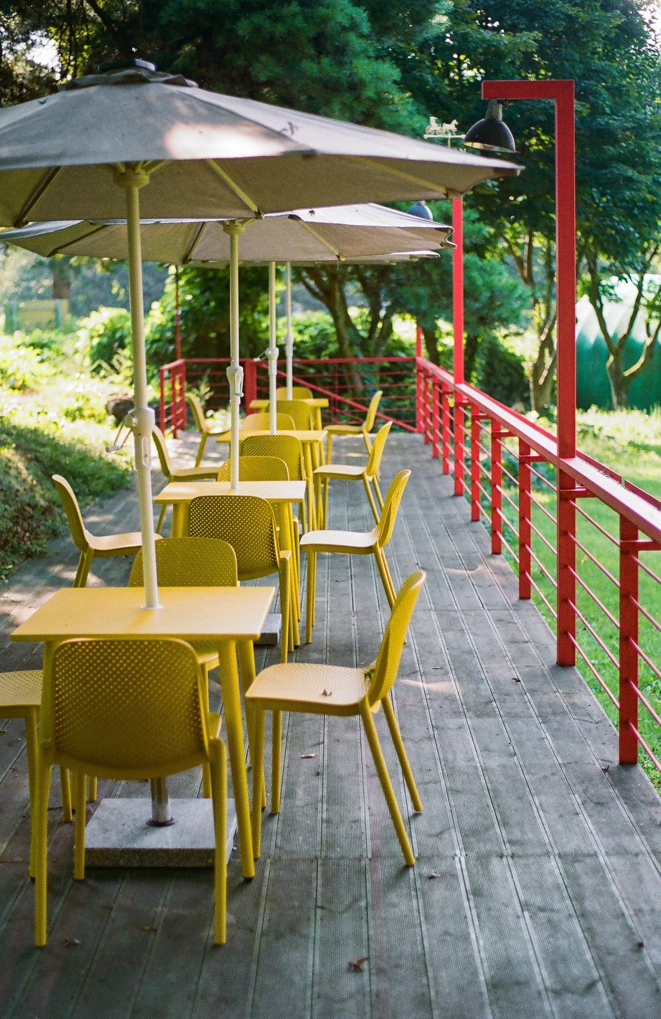 Outdoor terrace of museum venue hosting Burnsoo Song exhibition — yellow chairs and umbrellas, green trees