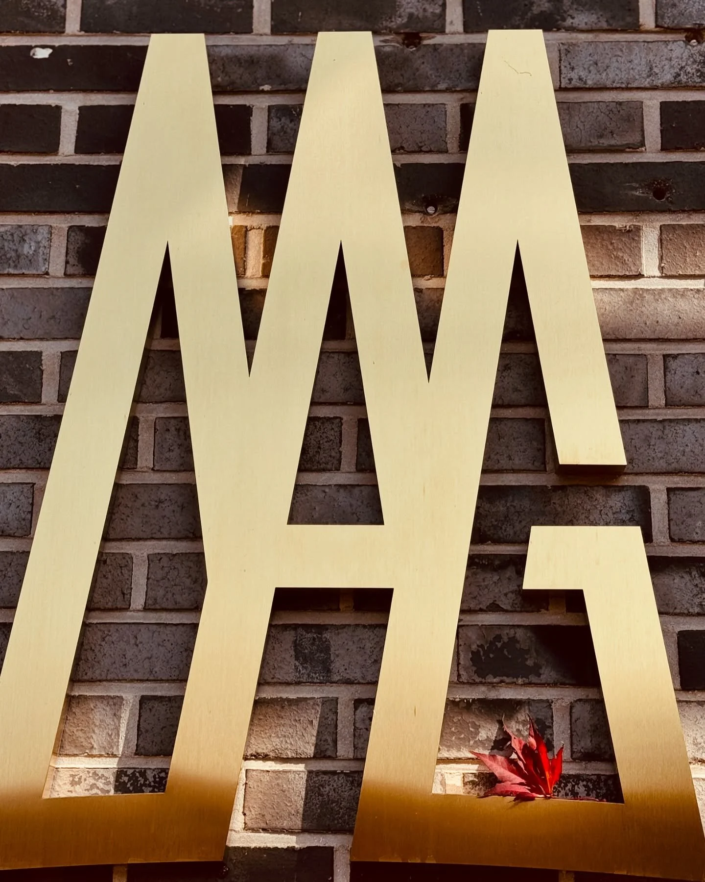 Gold decorative letter A sculpture at museum venue hosting Burnsoo Song exhibition, autumn setting