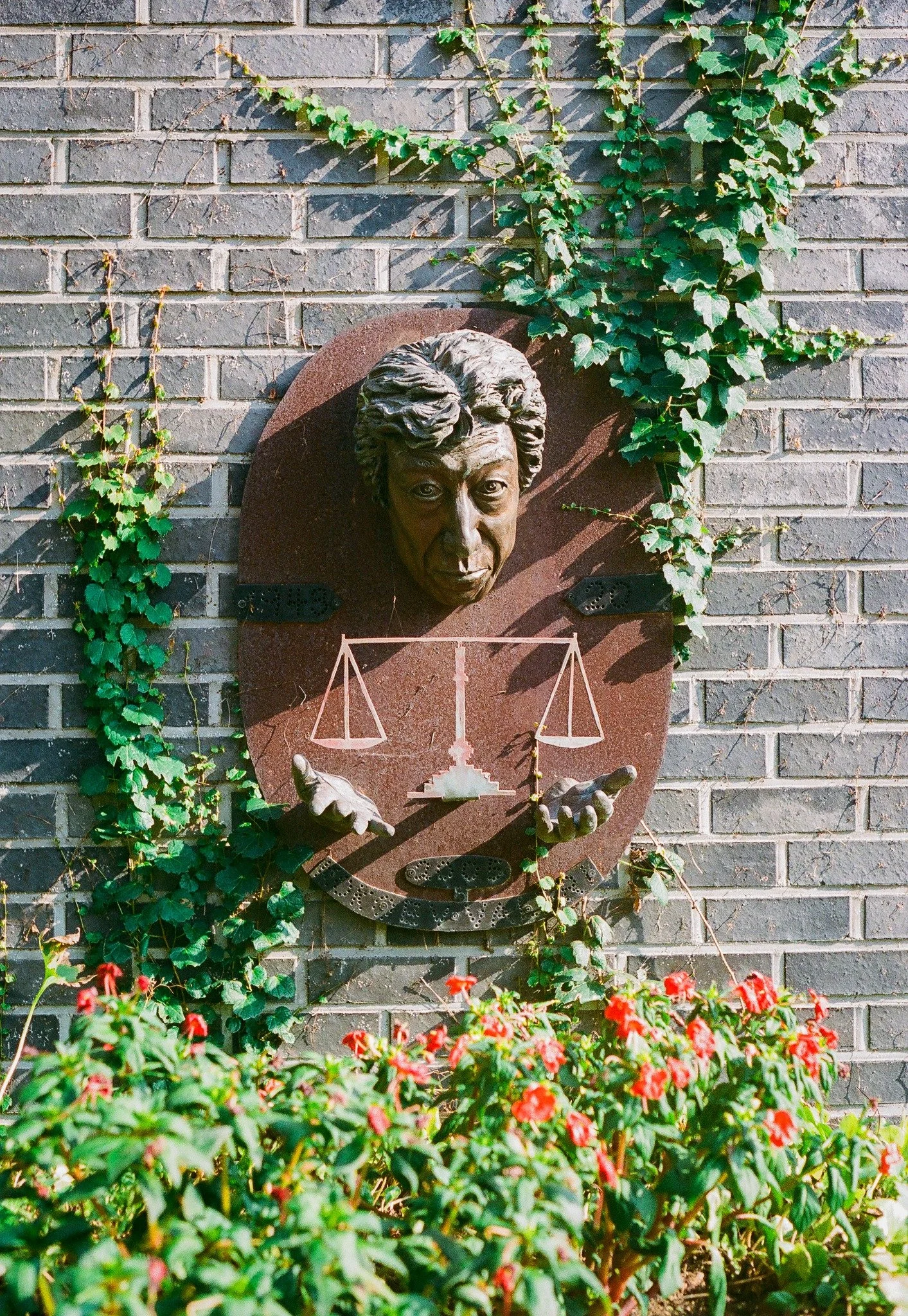 Bronze bust sculpture on ivy-covered brick wall at museum venue hosting Burnsoo Song exhibition