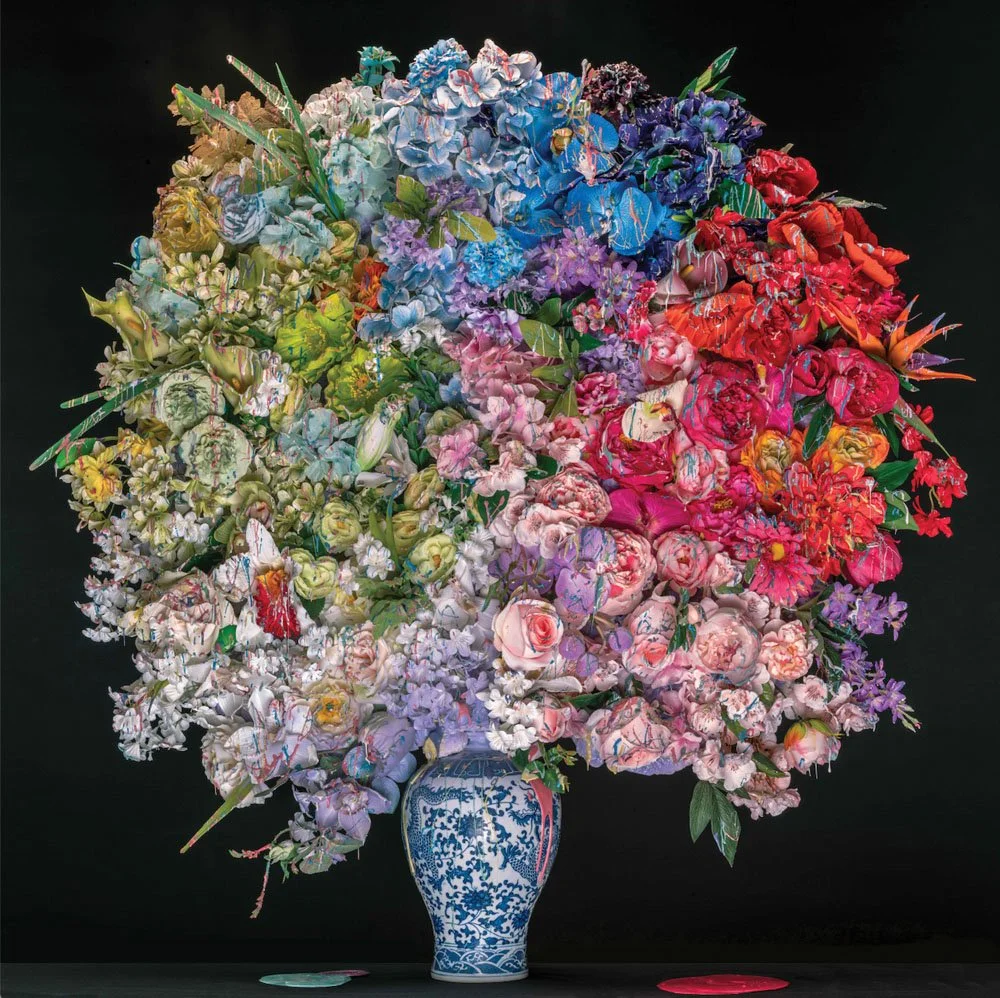A large, colorful bouquet of various flowers in a blue and white ceramic vase against a black background.