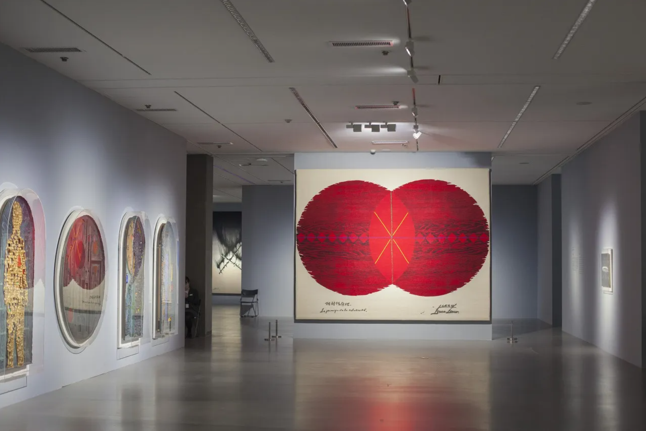 Gallery installation by Burnsoo Song featuring large red heart artwork and circular works on side wall