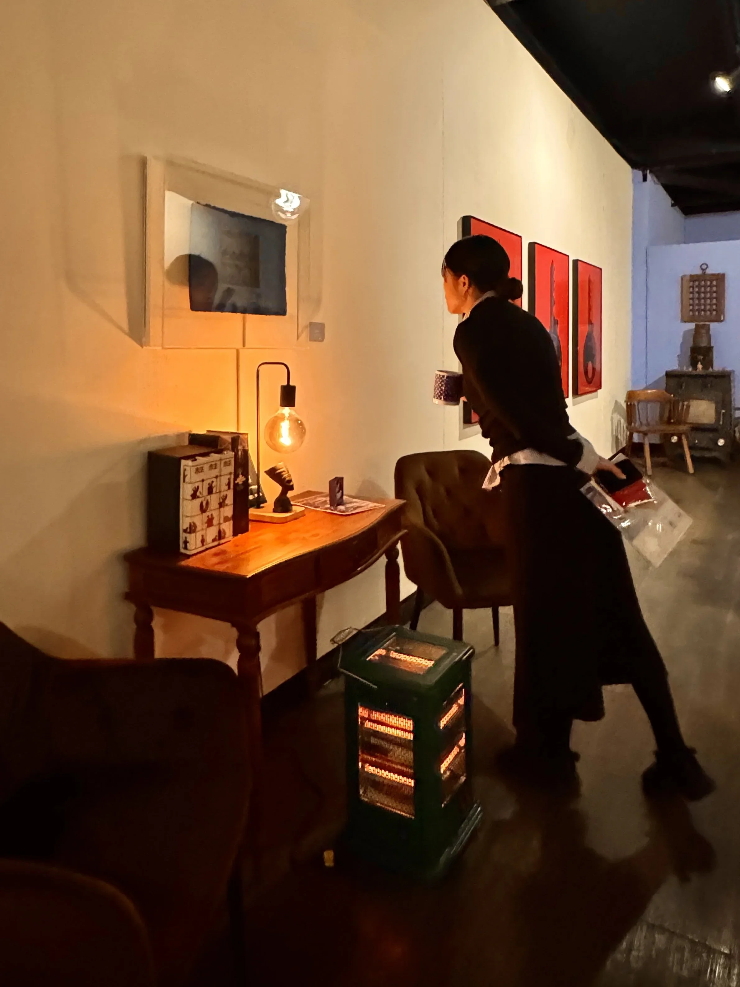 Visitor at a Burnsoo Song exhibition installation, dimly lit gallery space