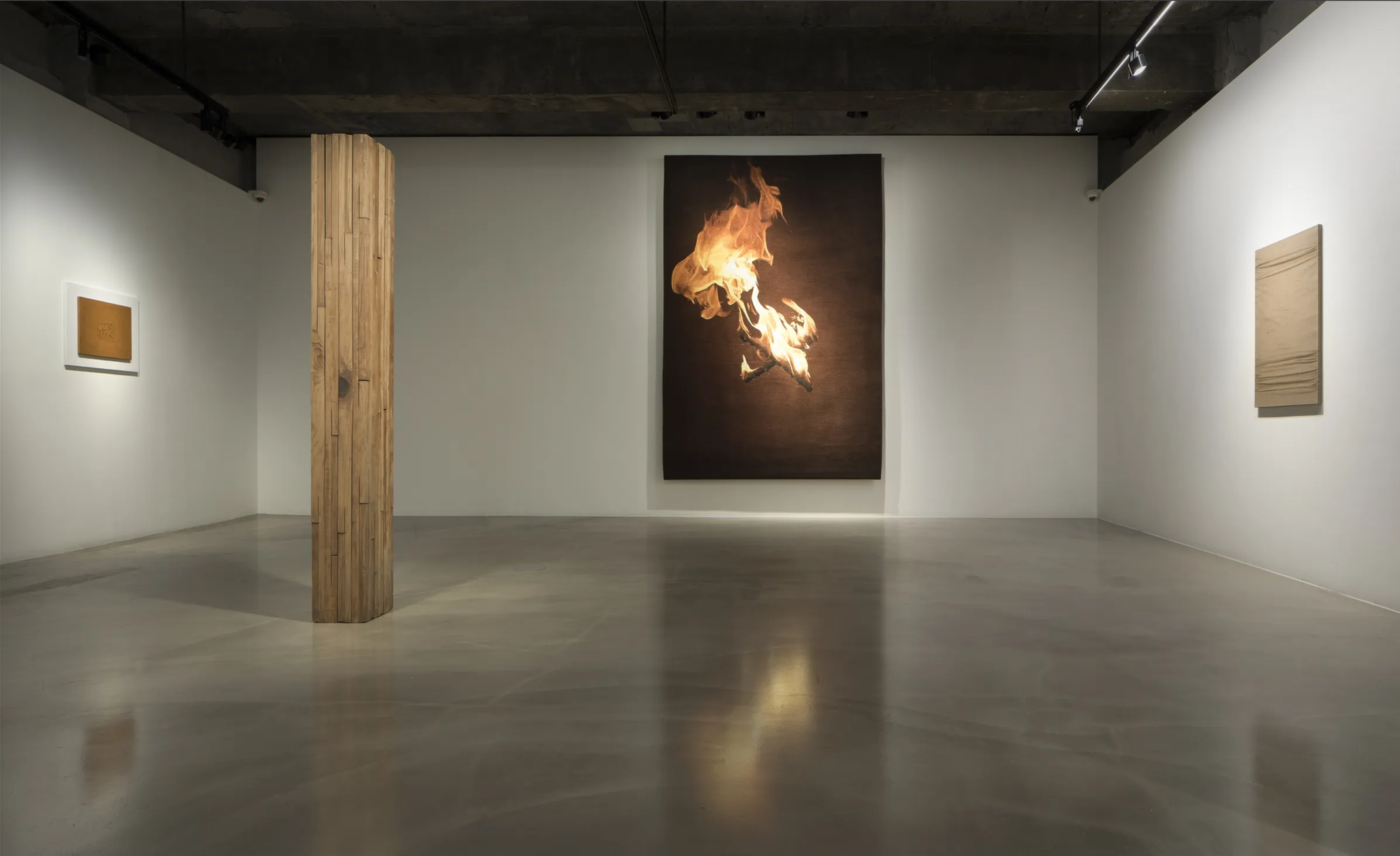 Gallery interior with Burnsoo Song tapestry depicting flames at centre, fiber art installation, white gallery walls