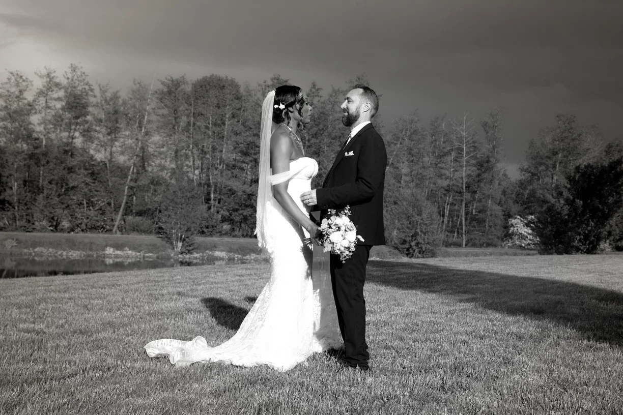 Les mariés se regardent dans un jardin au coucher du soleil, portrait de couple en noir et blanc réalisé lors d'un reportage de mariage en Suisse, mettant en valeur leur complicité et l'élégance du moment.