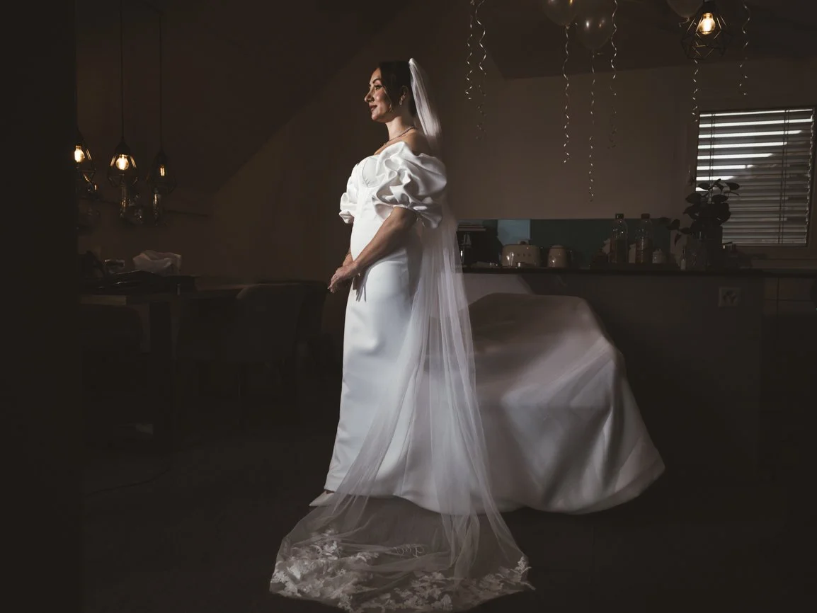 Portrait d'une mariée en robe de mariage pendant les préparatifs, mis en valeur par une lumière dramatique et une ambiance élégante avant la cérémonie en Suisse.