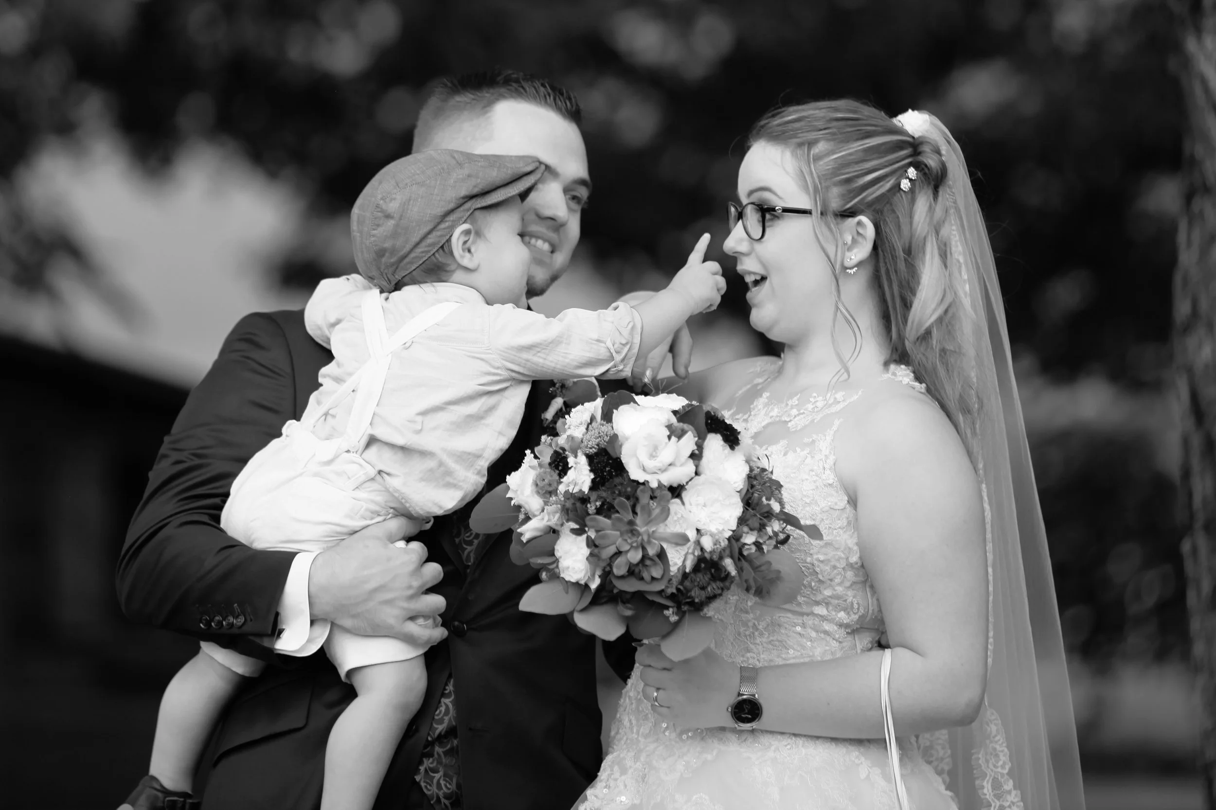 Le marié retrouve un proche dans une étreinte remplie de joie et d'émotion, photographie de mariage en noir et blanc capturant un moment authentique et spontané lors de la réception