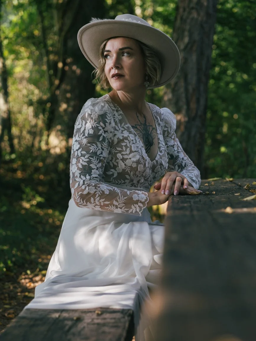 Portrait d'une mariée au style bohème portant un chapeau, photographiée en lumière naturelle dans une forêt lors d'un mariage en Suisse, entre élégance et authenticité.