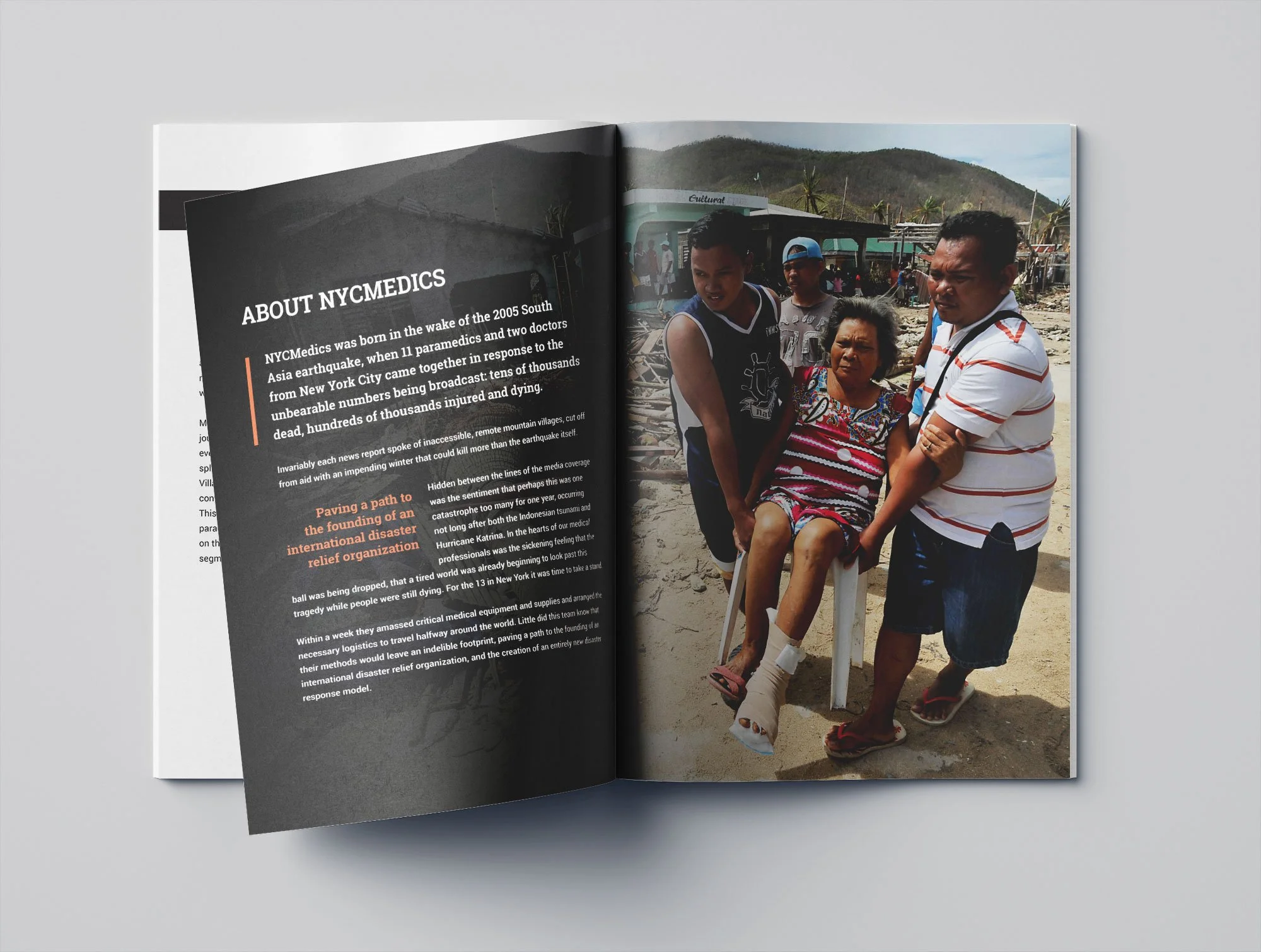 In a magazine, a woman in a wheelchair is being assisted by several men on a sandy, wreckage-filled area with mountains in the background. The woman appears to be injured, and the men are helping her. There are others in the background, and the scene appears to be outdoors in a rural or disaster-affected area.