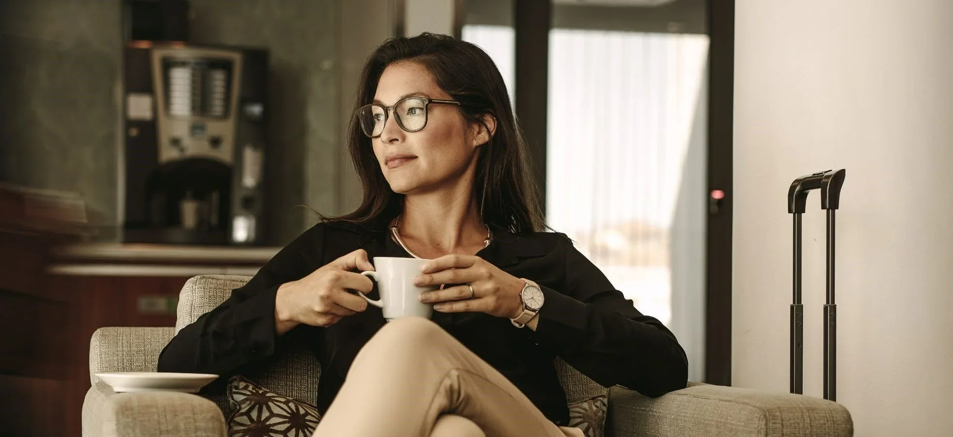 Image of woman sat in an airport waiting lounge drinking a coffee