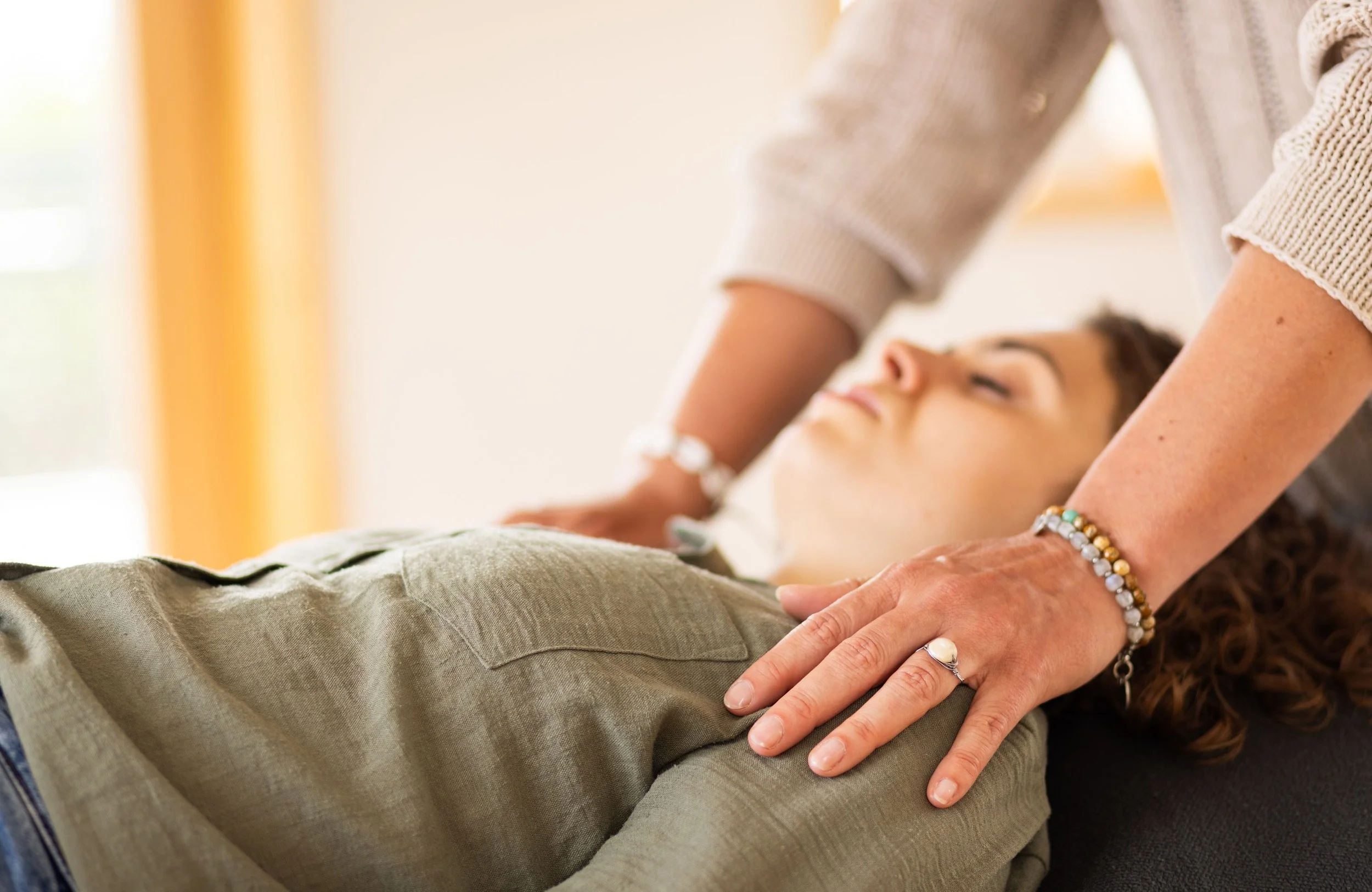 A person receiving a reiki treatment from another person, focusing on the hands and arms of both individuals.