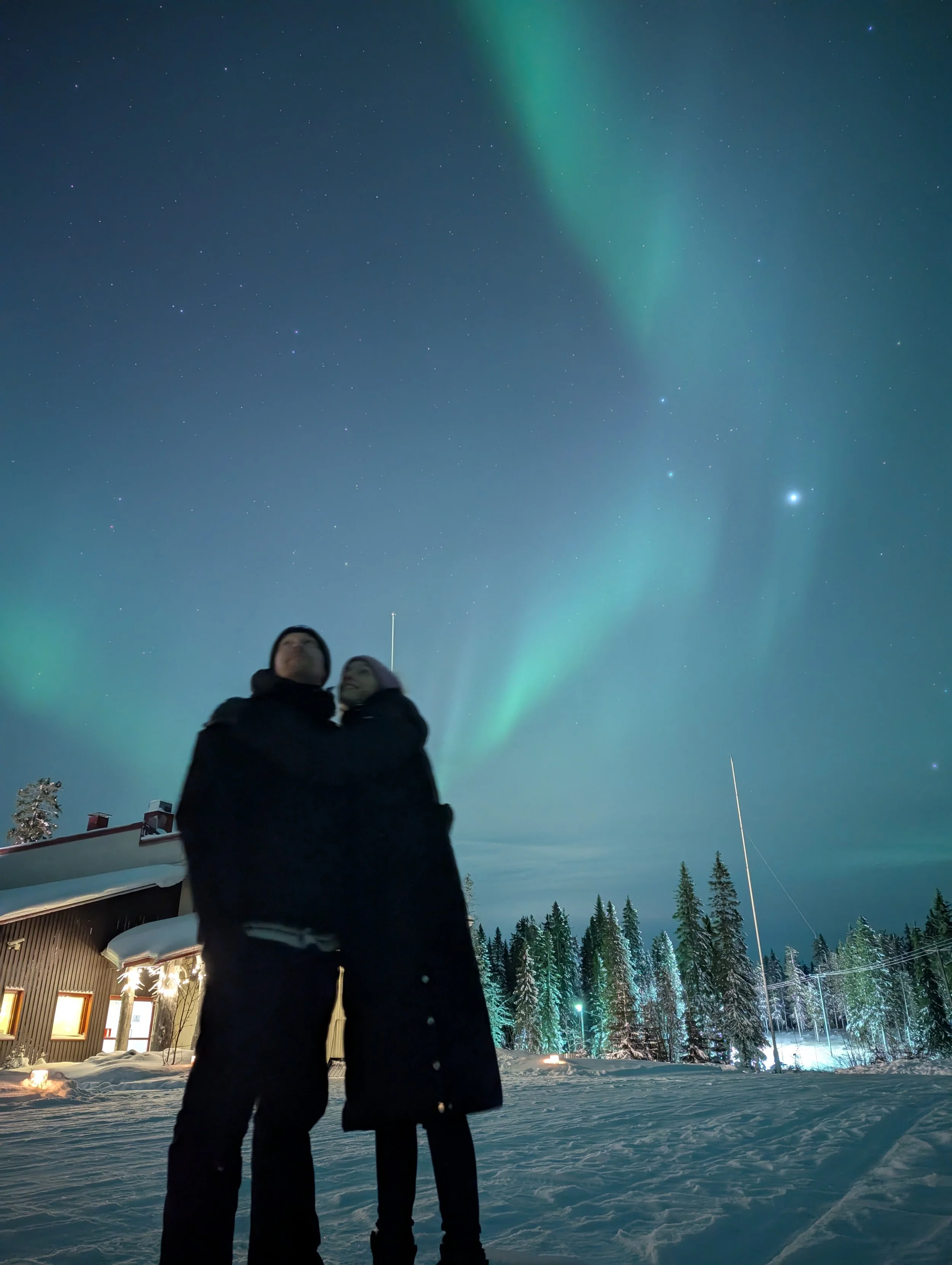 couple standing beneath northern lights, Finland