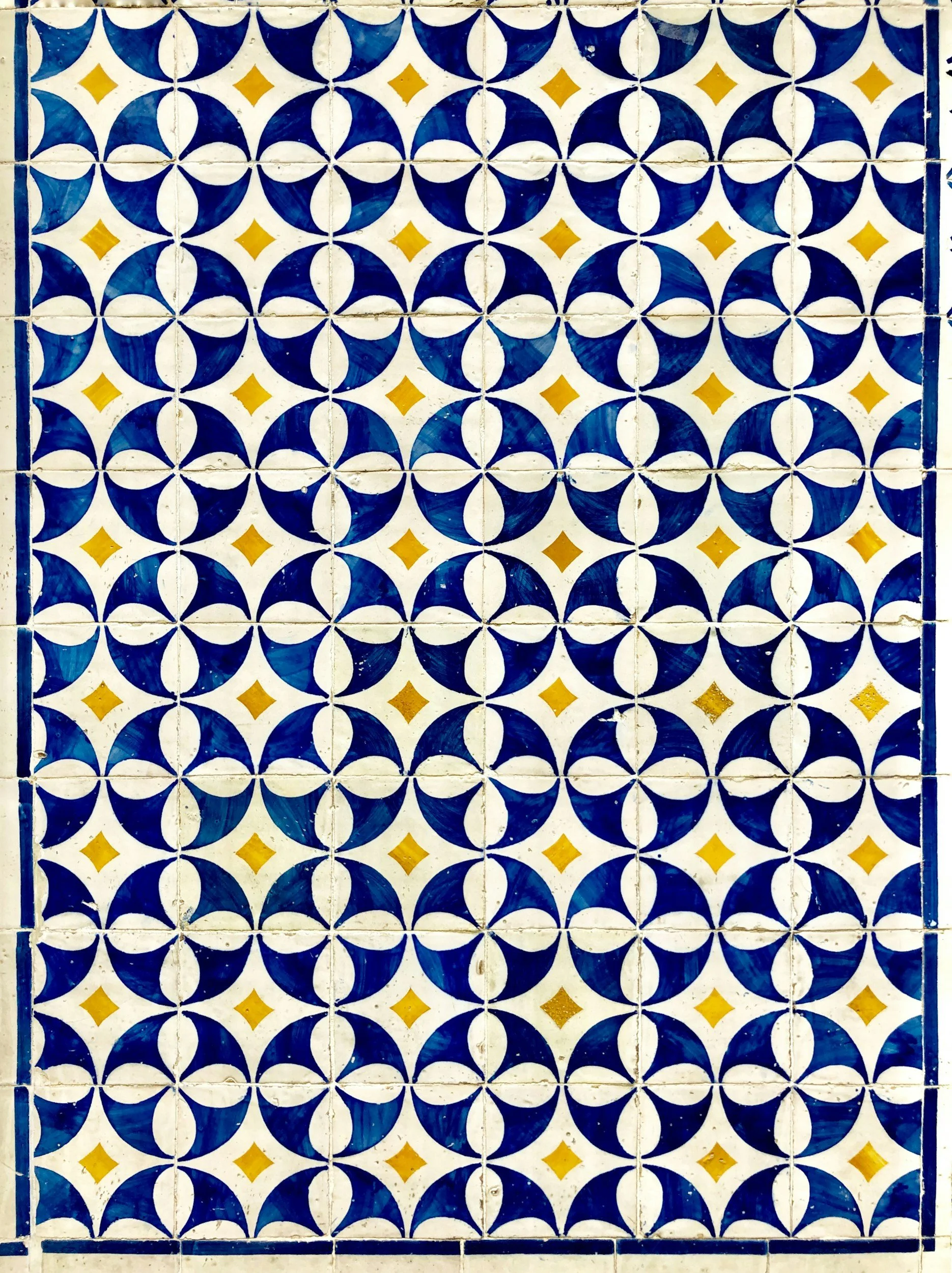 Pattern of blue and white geometric tiles with small yellow diamond shapes.