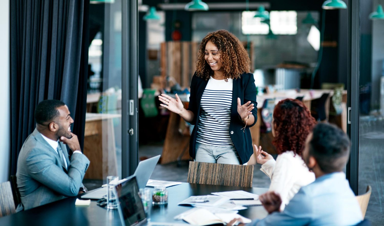 Woman giving a presentation to a group of colleagues in a conference room.