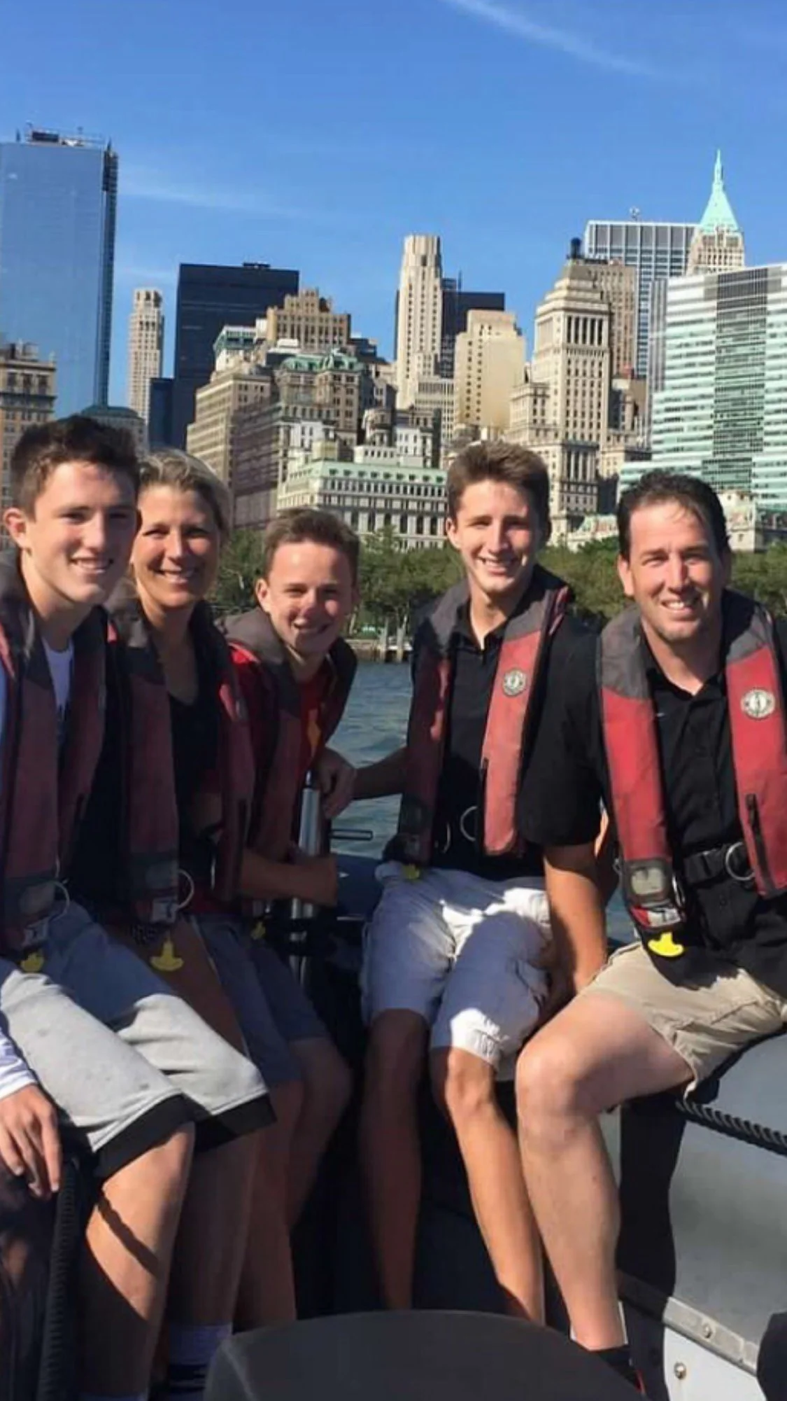 The Etchison family sitting on a boat with New York City skyline in the background