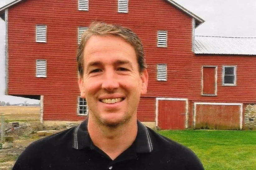 Tony Etchison smiling in front of a barn