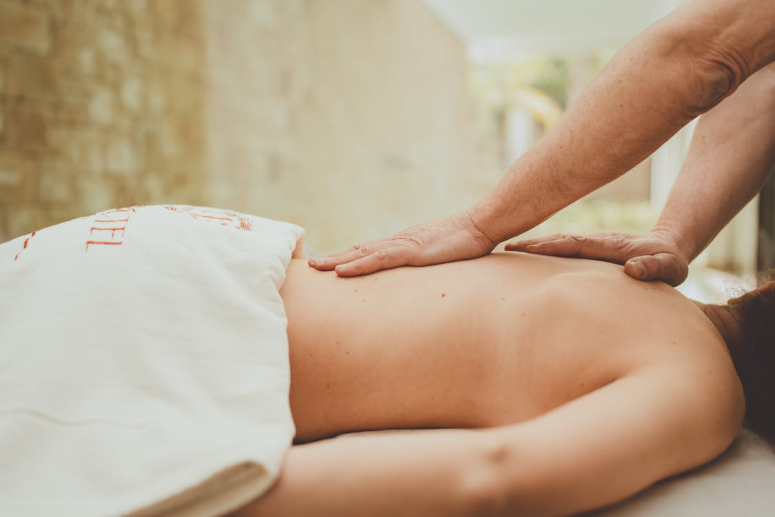 Jemand erhält eine Rückenmassage auf einem Bett im Freien.